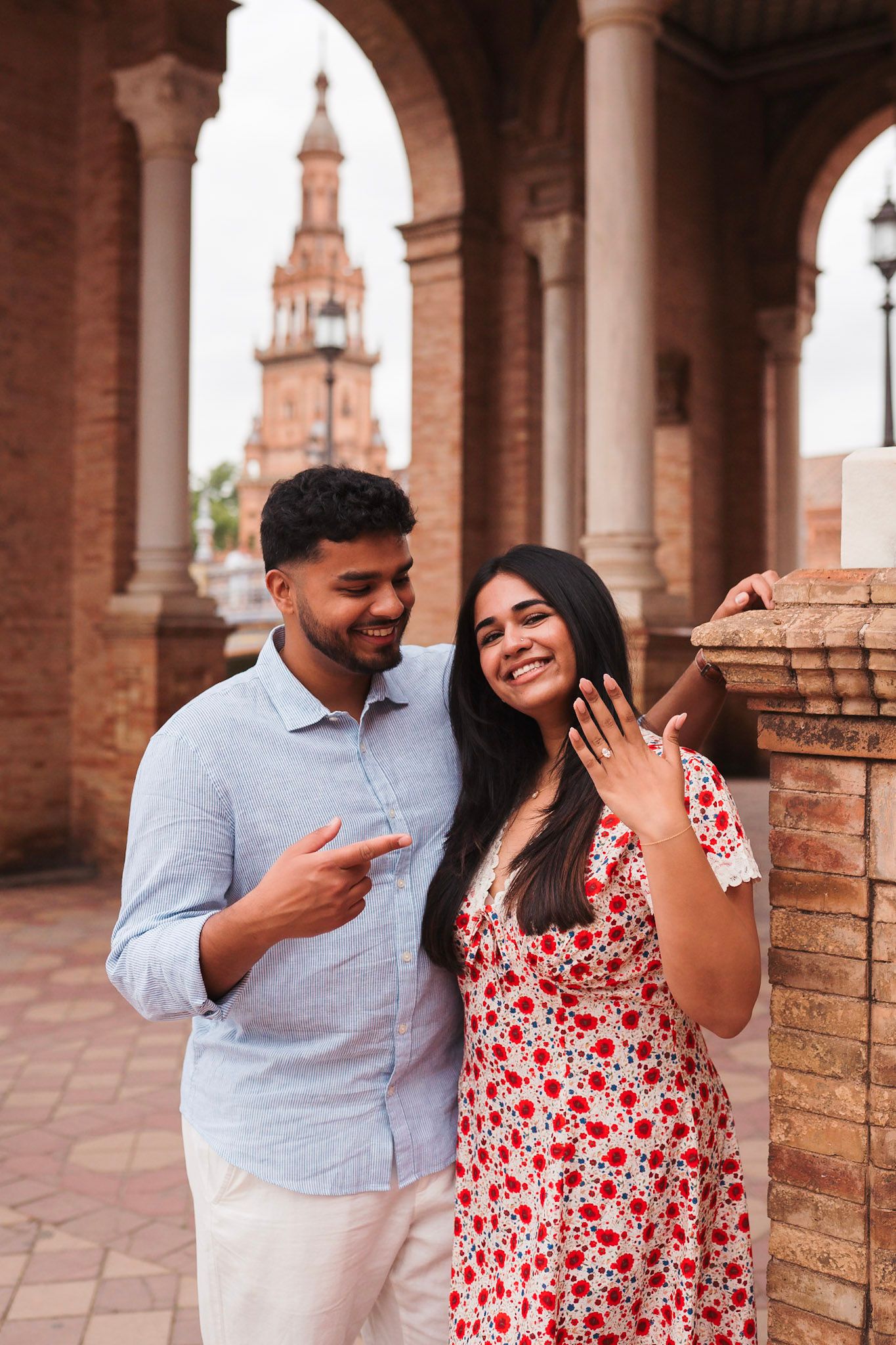 Happy couple showing engagement ring at Plaza de España, Seville, Spain.