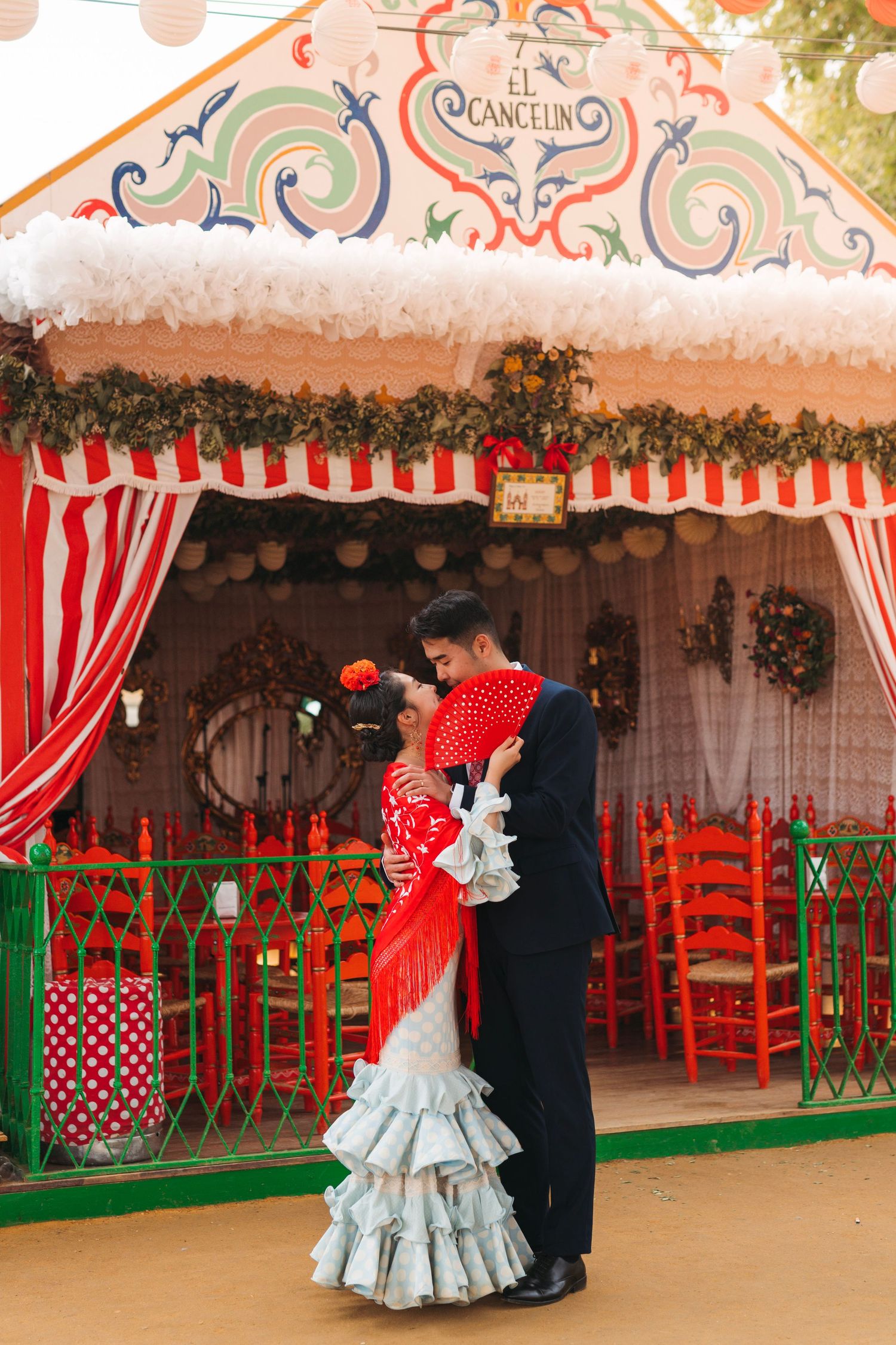 Couple embraces outside colorful El Cancelin caseta at Seville April Fair.