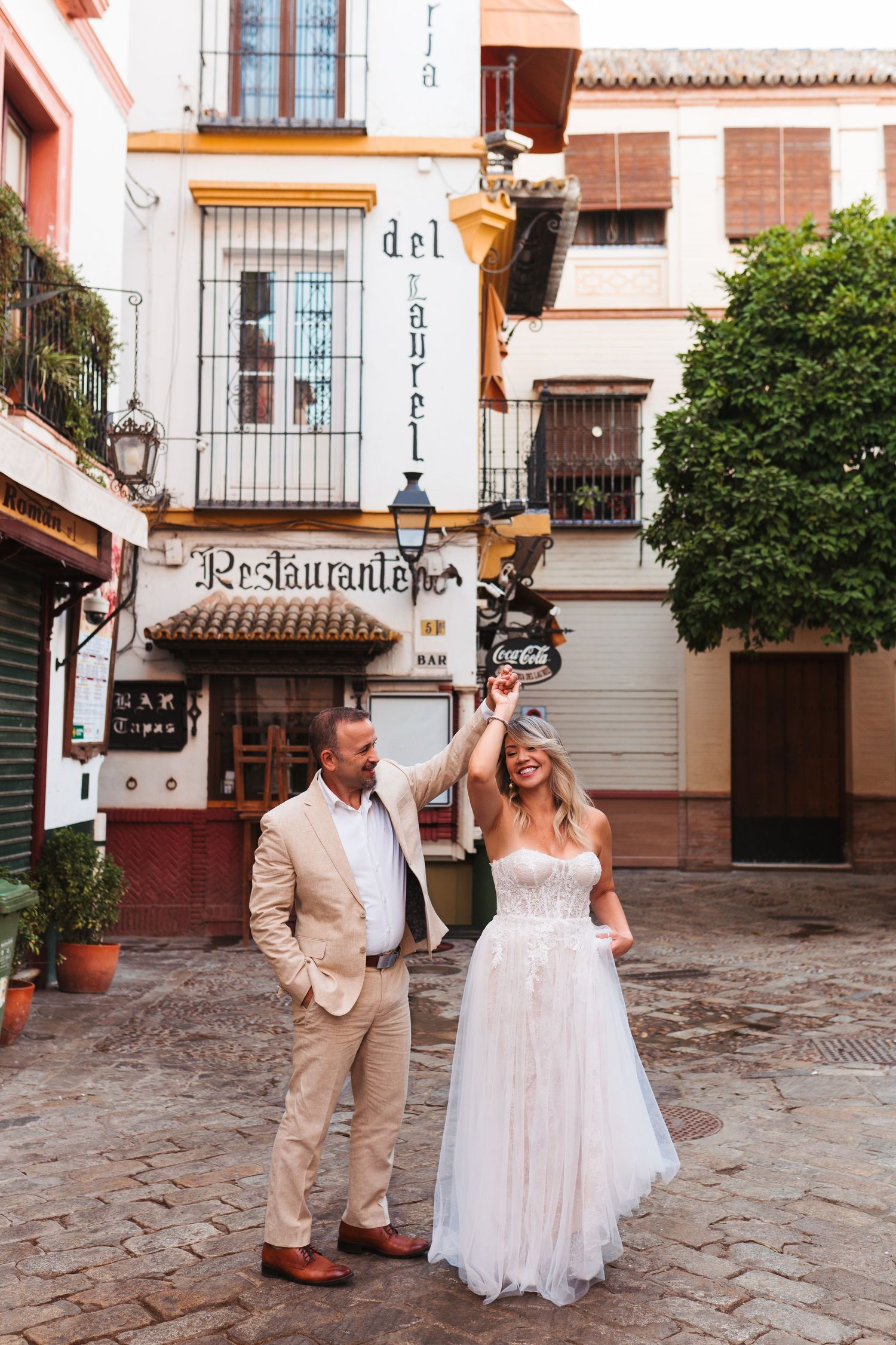 Bride and groom dancing in a charming Spanish plaza near Restaurante del Laurel in Seville, Spain.