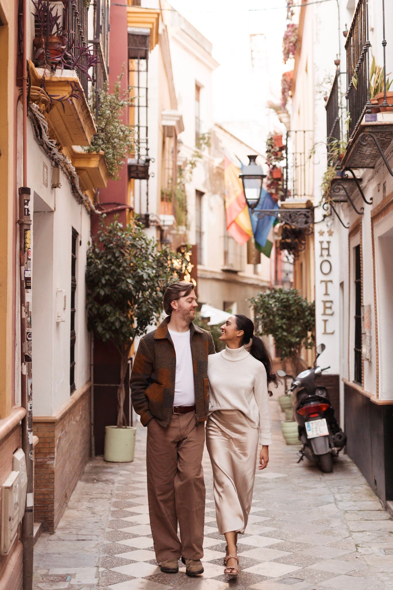 Romantic couple walking hand in hand through a charming narrow European street lined with hotels.