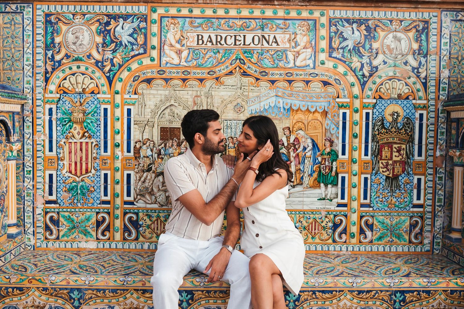 Couple sharing a tender moment on ornate Barcelona tile bench at Plaza de España, Seville.