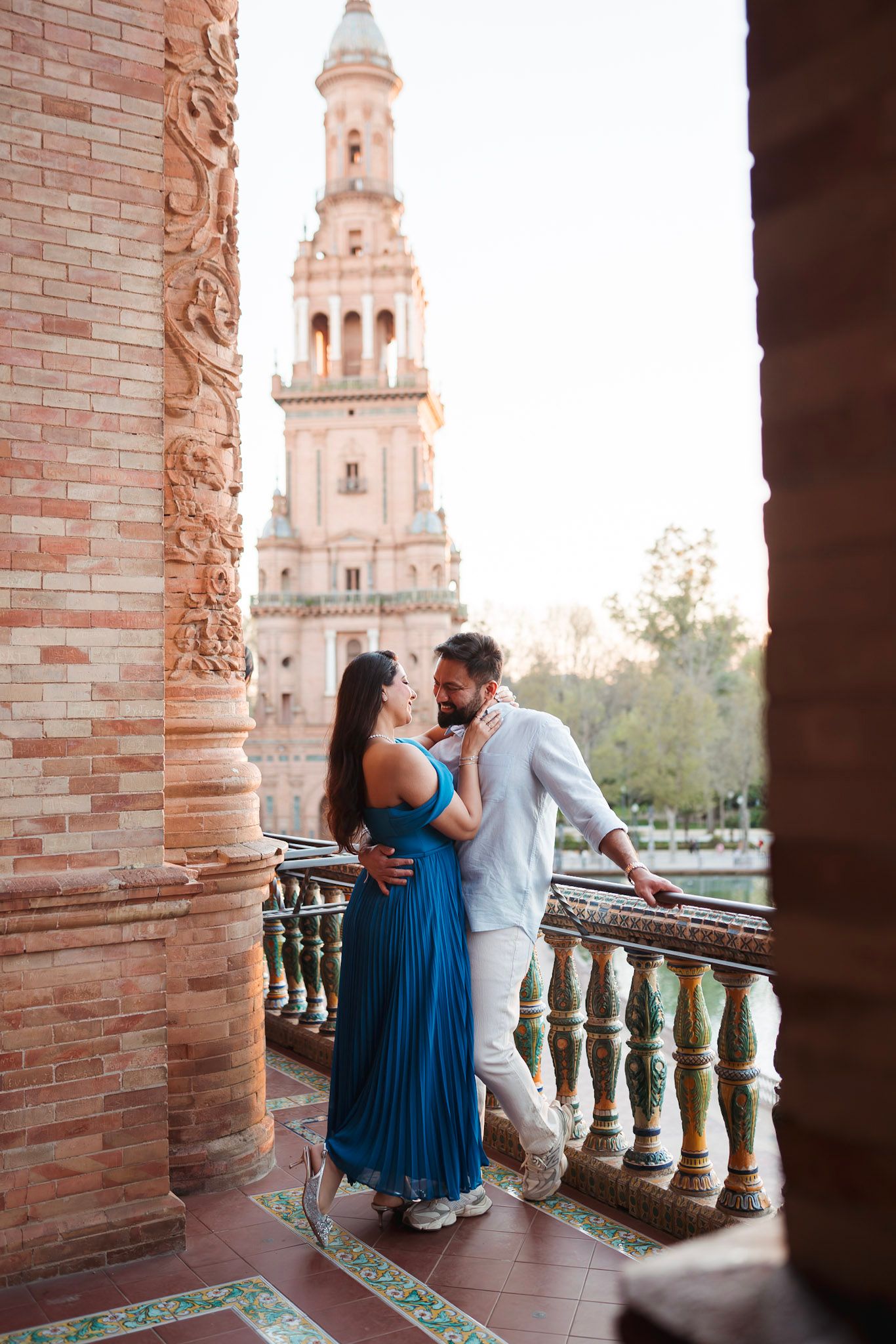 Couple sharing a tender moment on a decorative balcony framed by carved columns at Plaza de España.