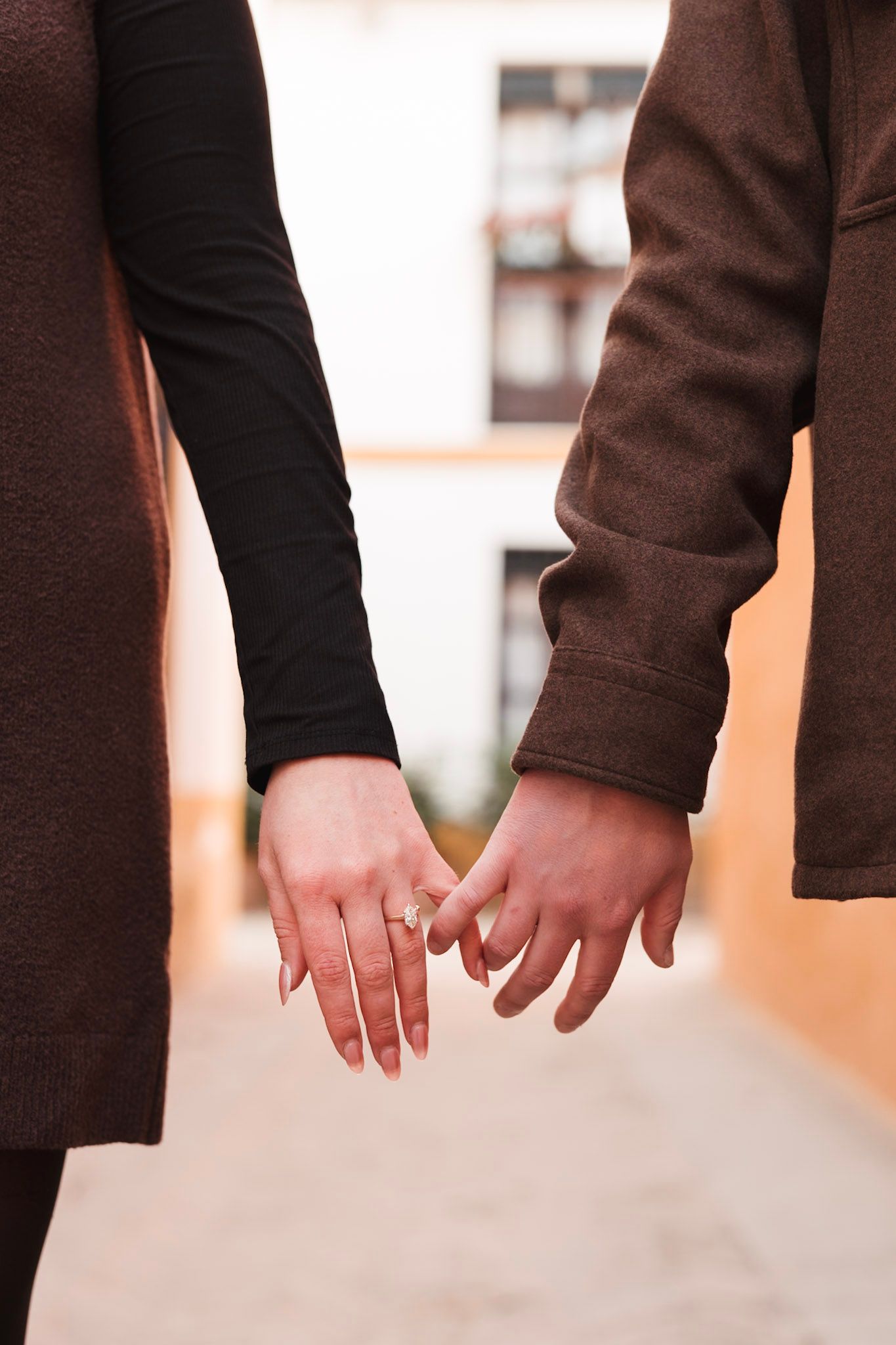 Close-up of newly engaged couple holding hands showing diamond engagement ring on her finger.