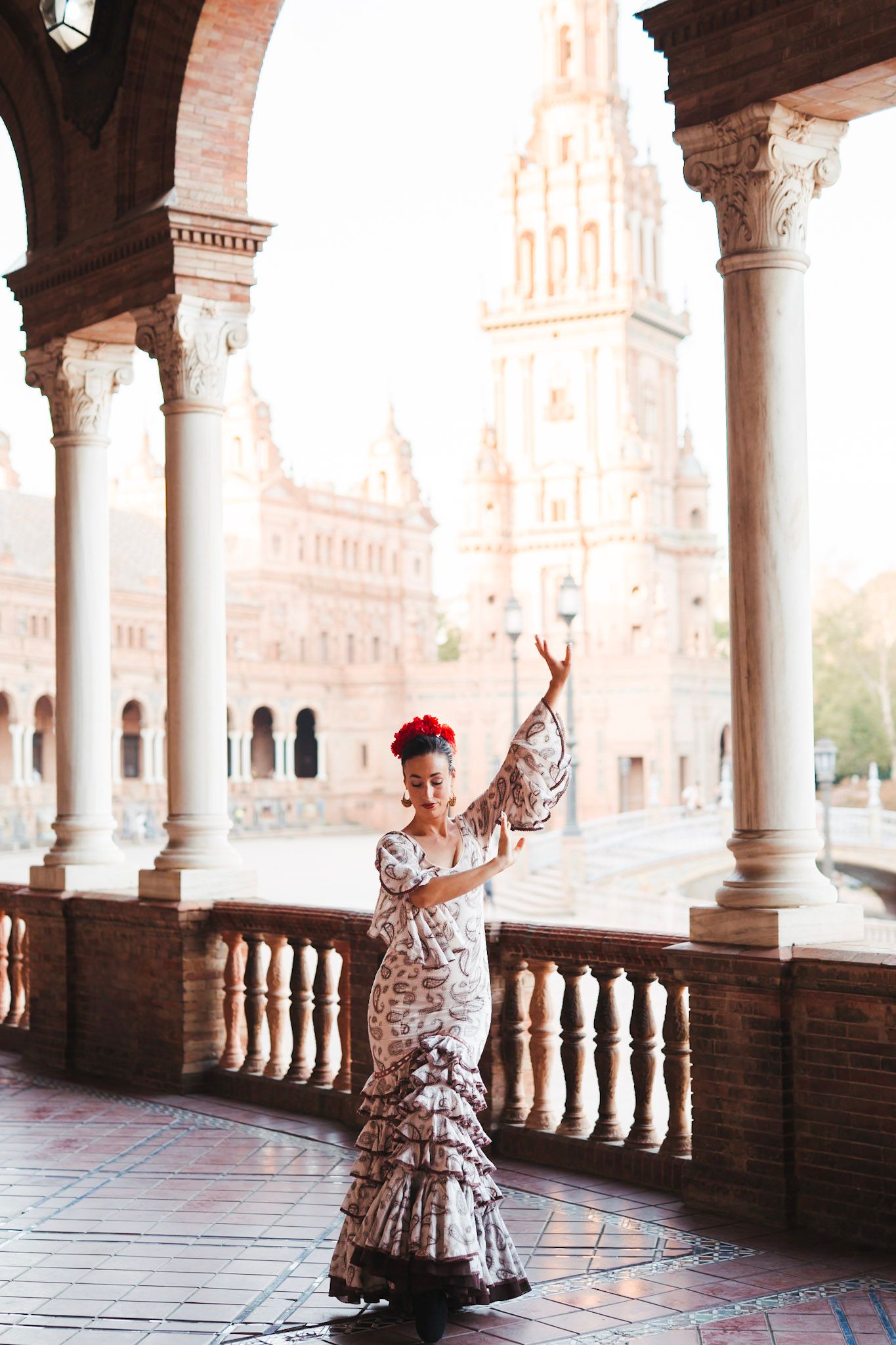 Elegant flamenco dancer in patterned dress poses gracefully at Plaza de Espana, Seville.