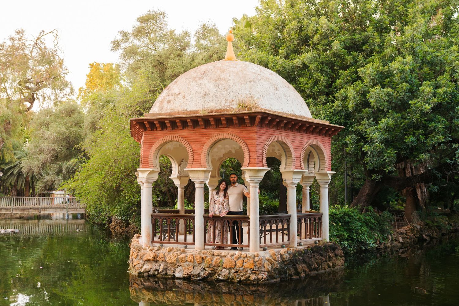 Couple embracing inside ornate Moorish pavilion on water at Parque de Maria Luisa, Seville, Spain.