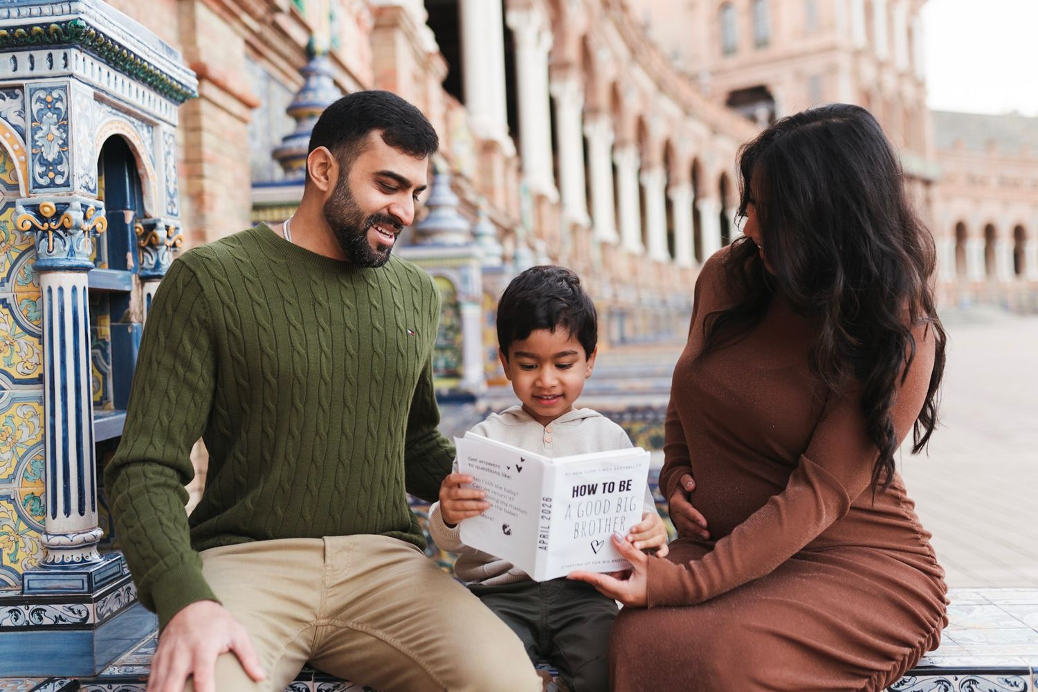Family maternity photo with parents and toddler reading at Plaza de España Seville.