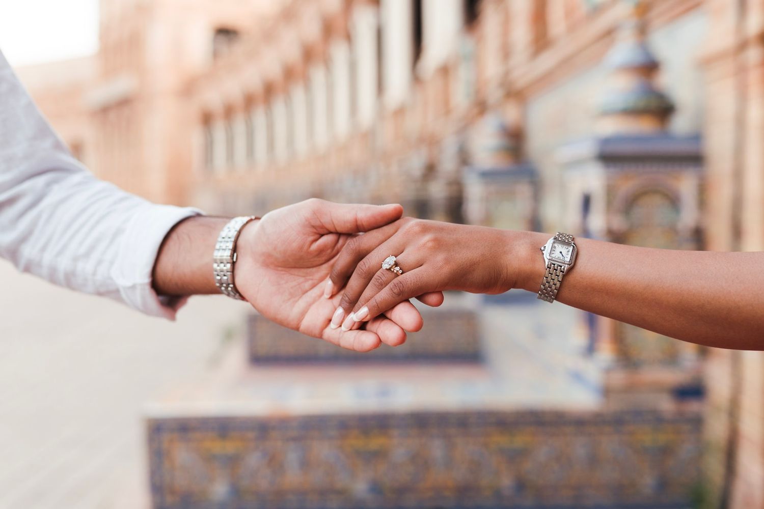 Close-up of couple holding hands showing engagement ring at Plaza de España Seville.
