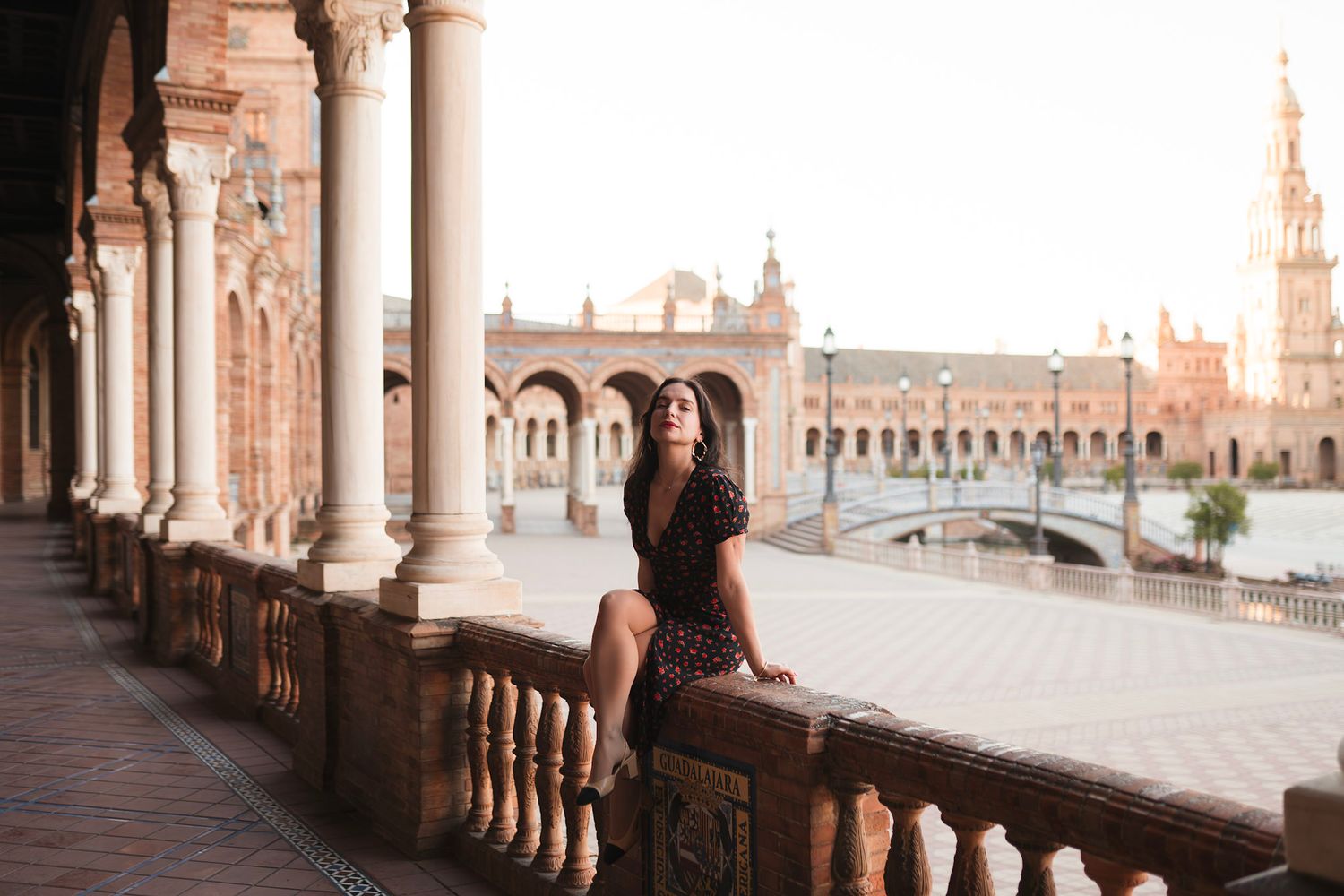 Young woman sitting on balustrade at Plaza de España, Seville, Spain.