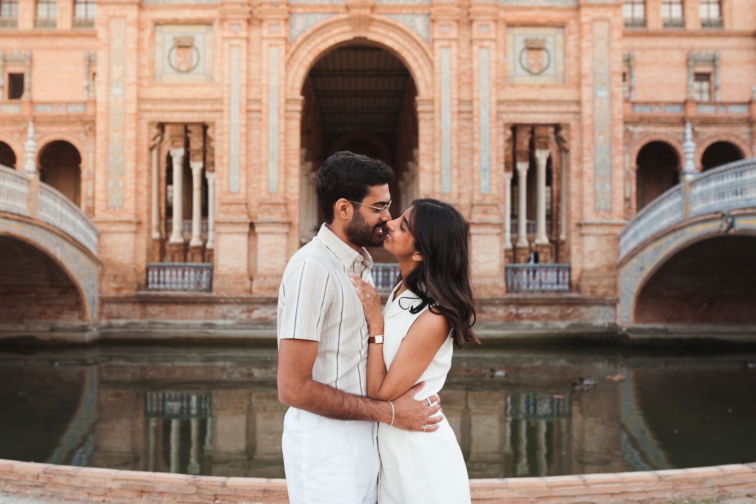 Romantic couple almost kissing in front of Plaza de España canal and colonnade in Seville, Spain.