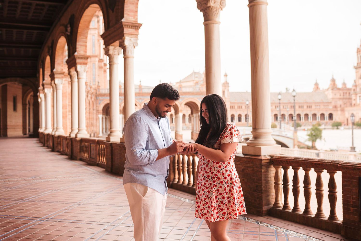 Couple sharing a romantic moment examining an engagement ring at Plaza de España in Seville.