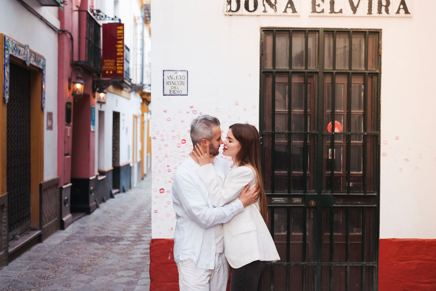Couple kissing outside Dona Elvira restaurant on a charming narrow street in Seville, Spain.