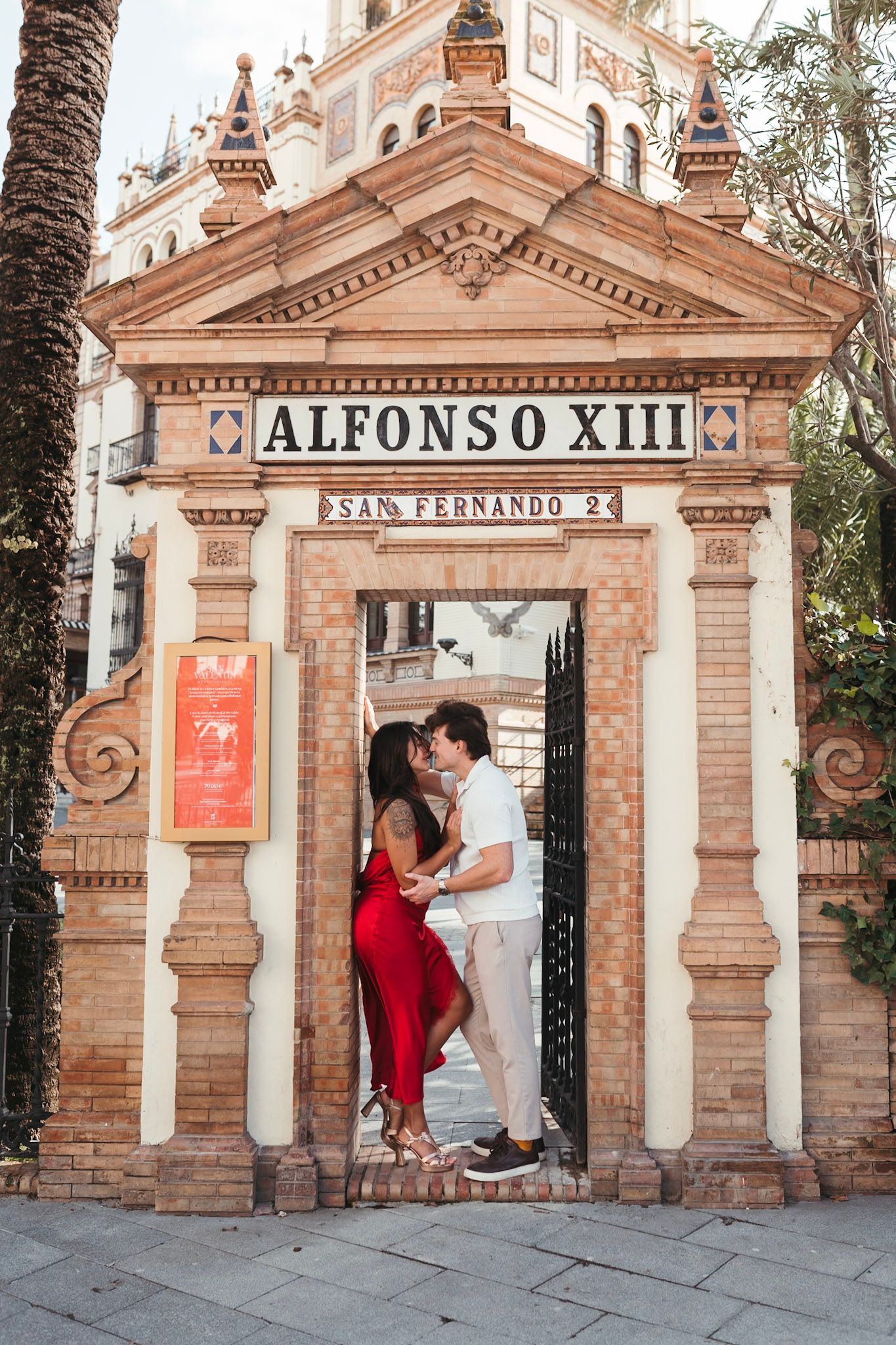 Couple kissing under the Alfonso XIII hotel entrance arch in Seville, Spain.