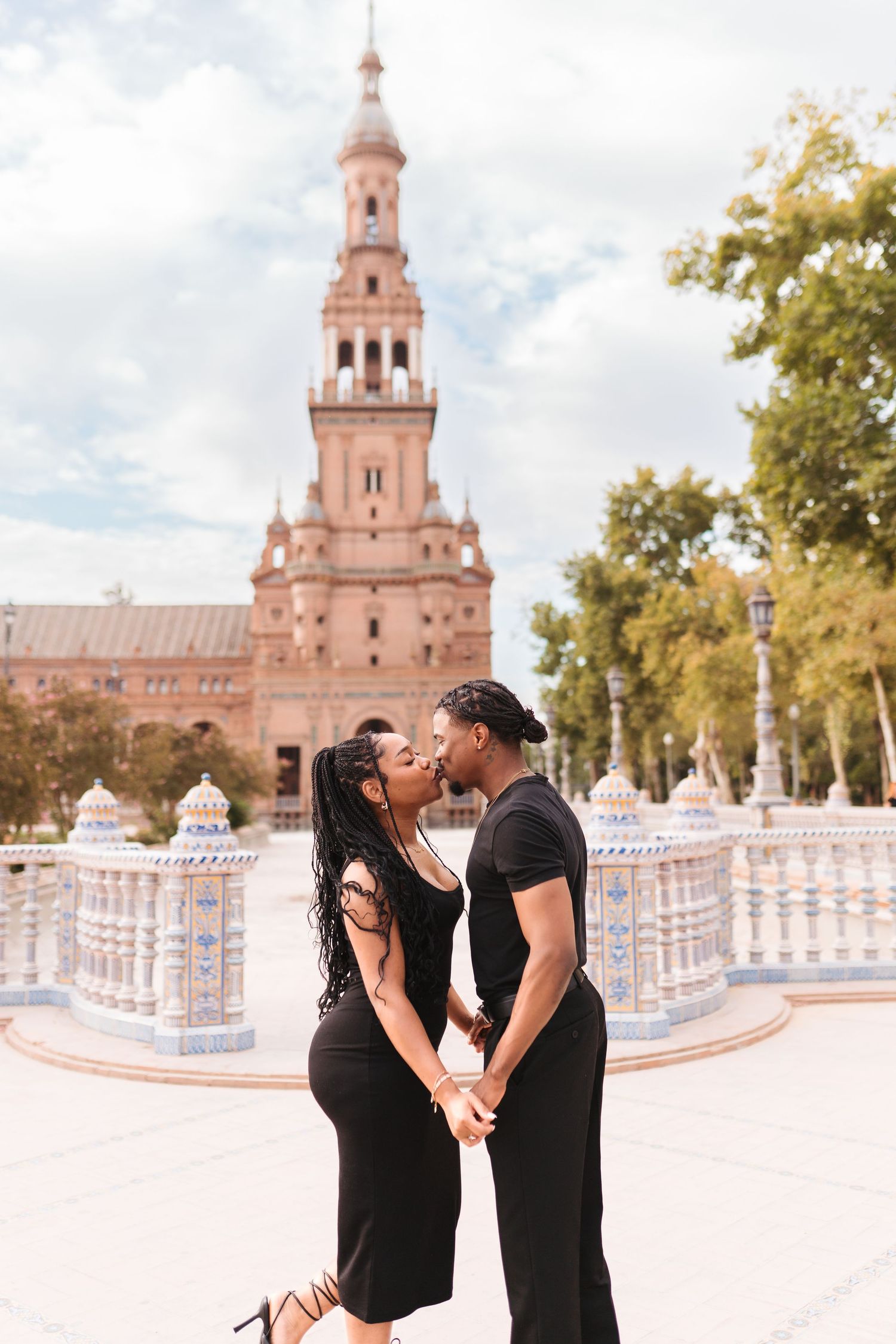 Romantic couple kissing at Plaza de España in Seville with iconic tower backdrop.