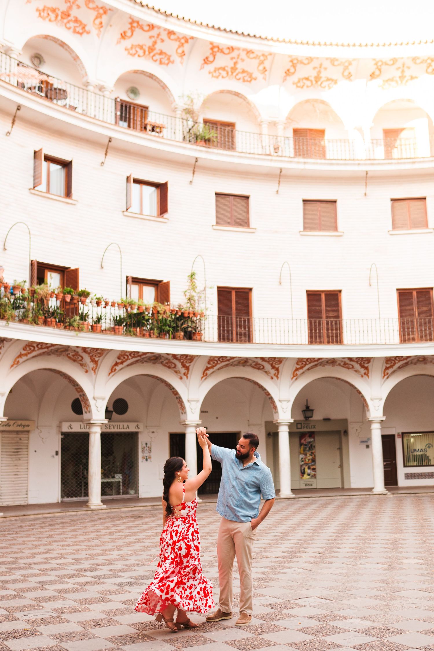 Couple dancing in a stunning white circular courtyard with arched colonnades and ornate balconies in Seville, Spain.