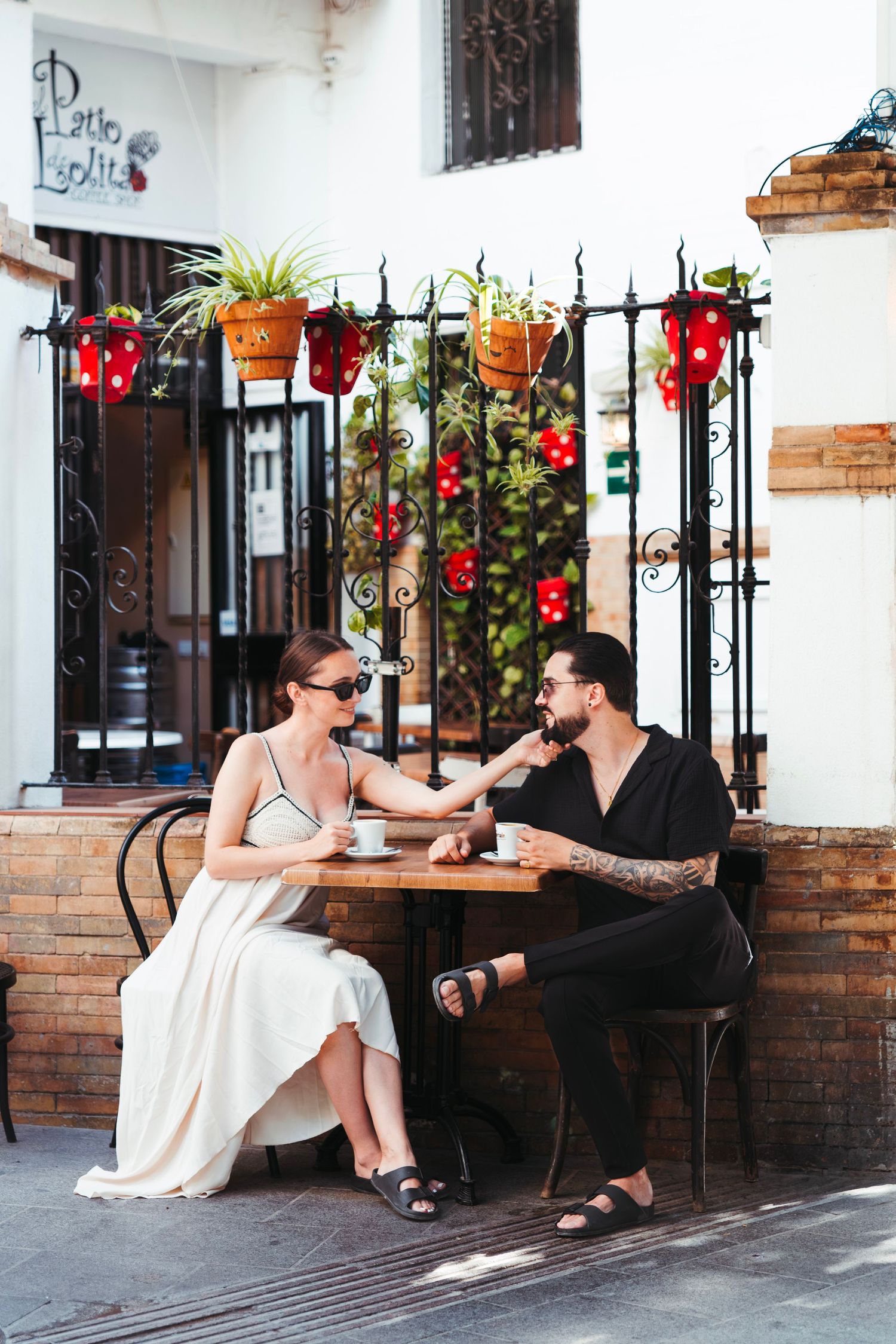 Romantic couple enjoying coffee at charming outdoor cafe with colorful flower decorations.