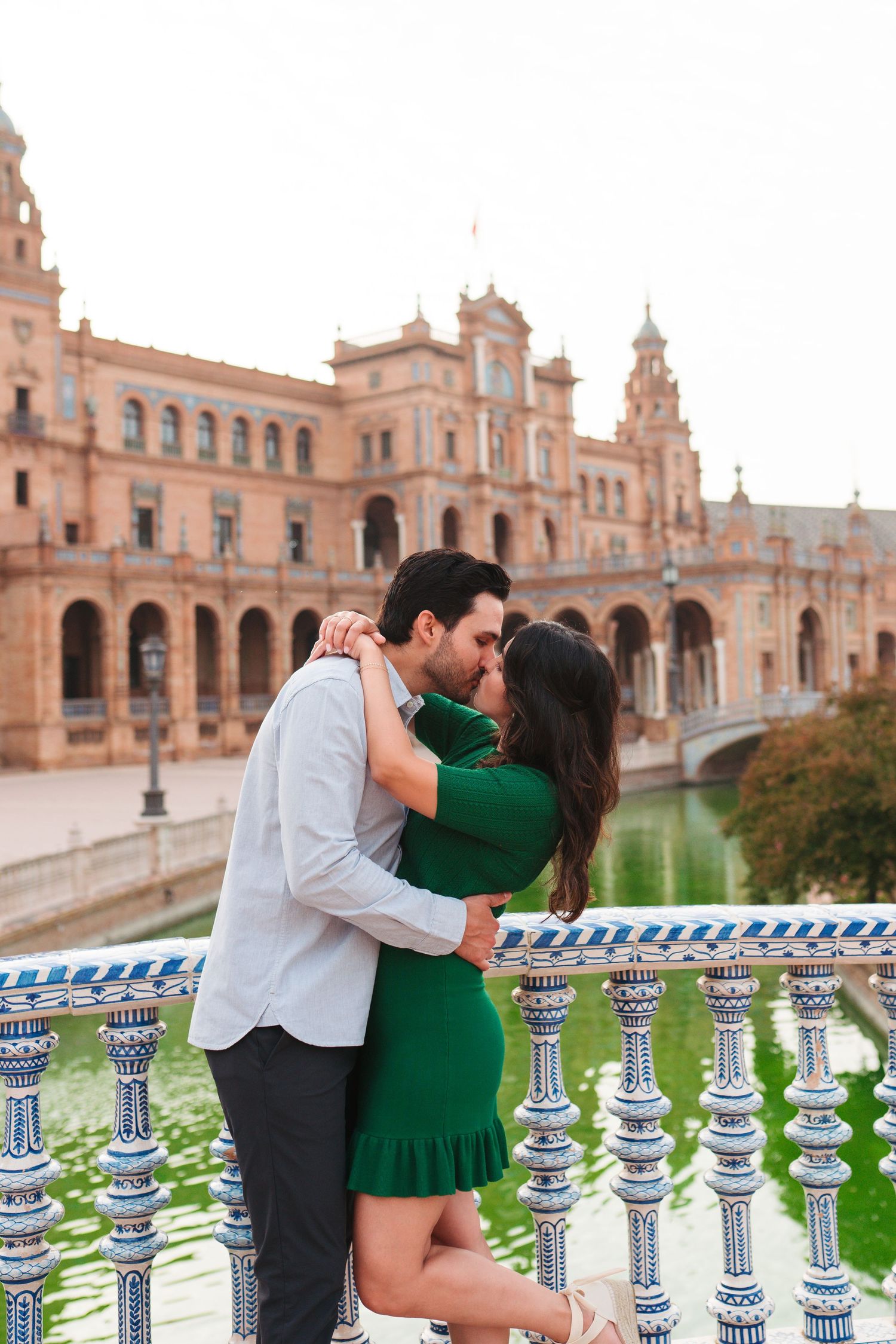 Couple kissing in green dress and white shirt at Plaza de España, Seville, Spain.
