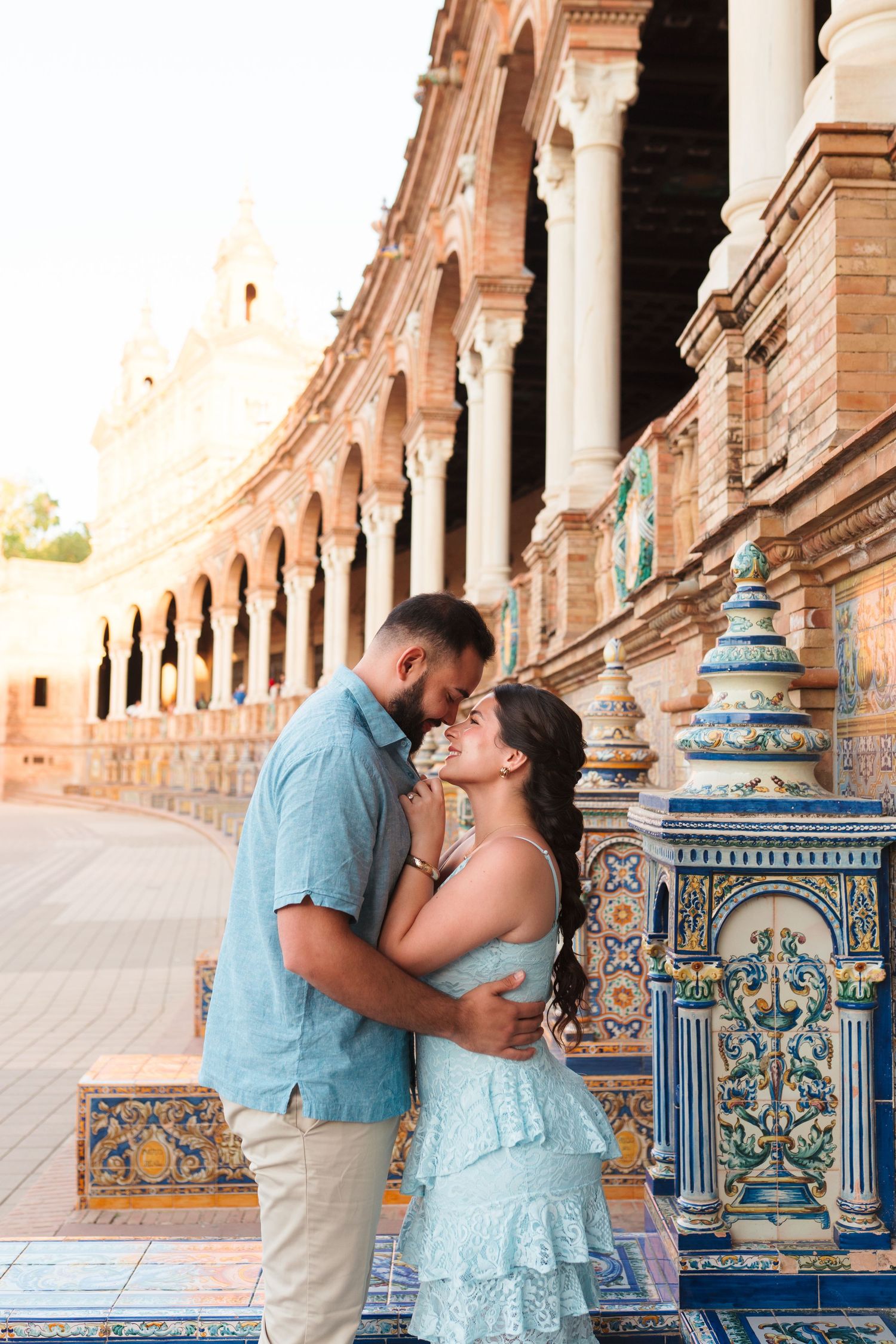 Couple sharing a romantic moment at Plaza de España in Seville, Spain, surrounded by ornate tiled benches and arches.