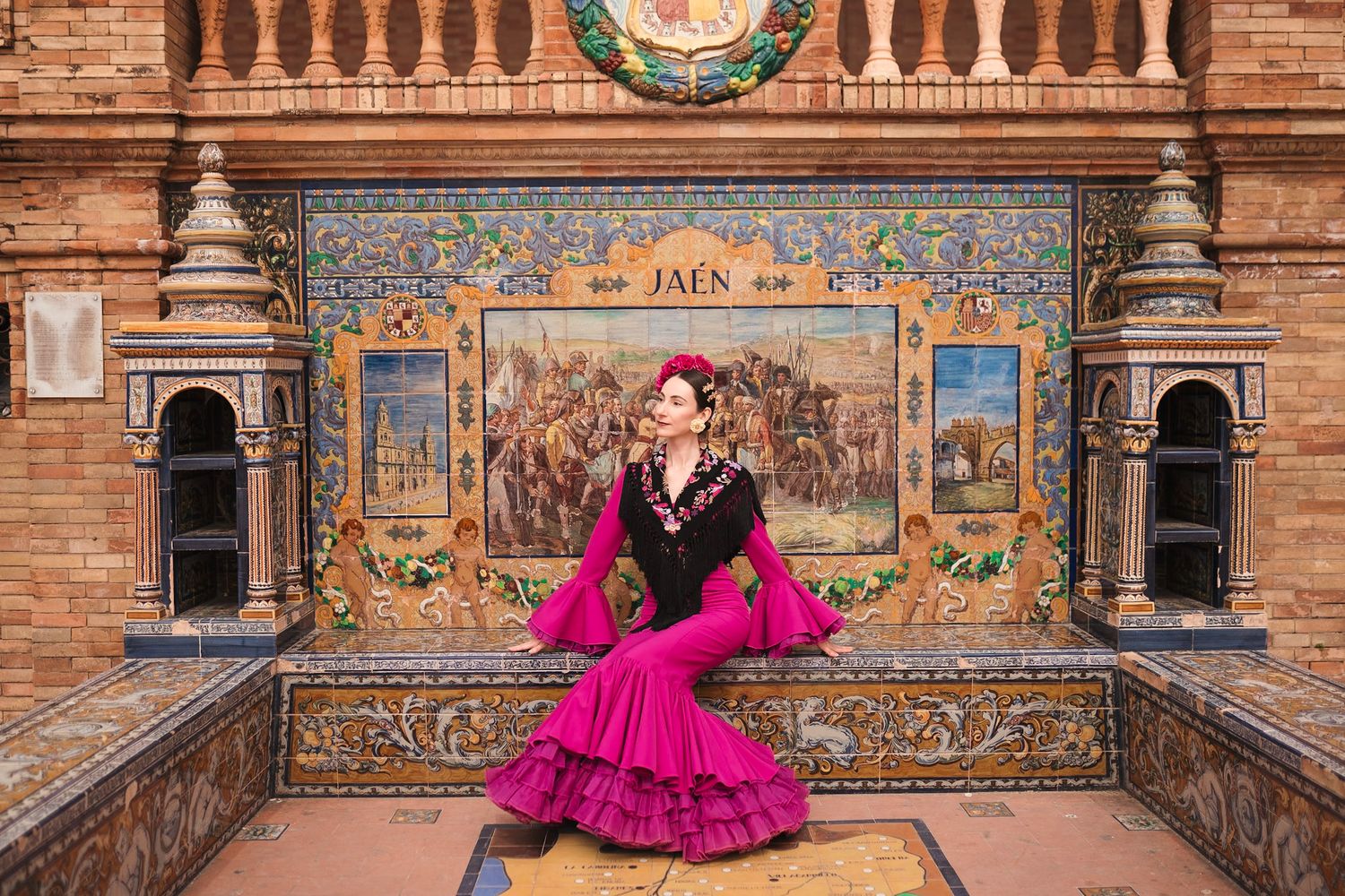 Flamenco dancer in magenta dress seated on ornate tiled bench at Plaza de España Seville Jaén alcove.
