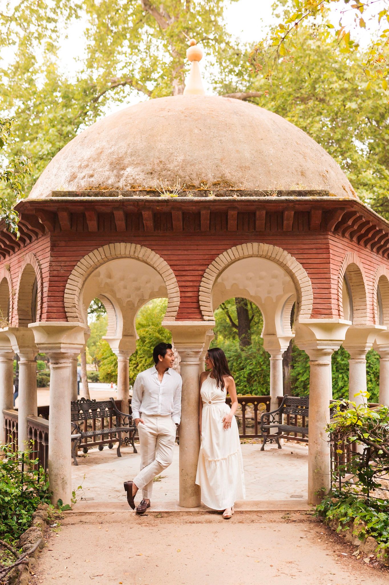 Couple sharing tender moment under arched Moorish pavilion in Parque de María Luisa, Seville, Spain.