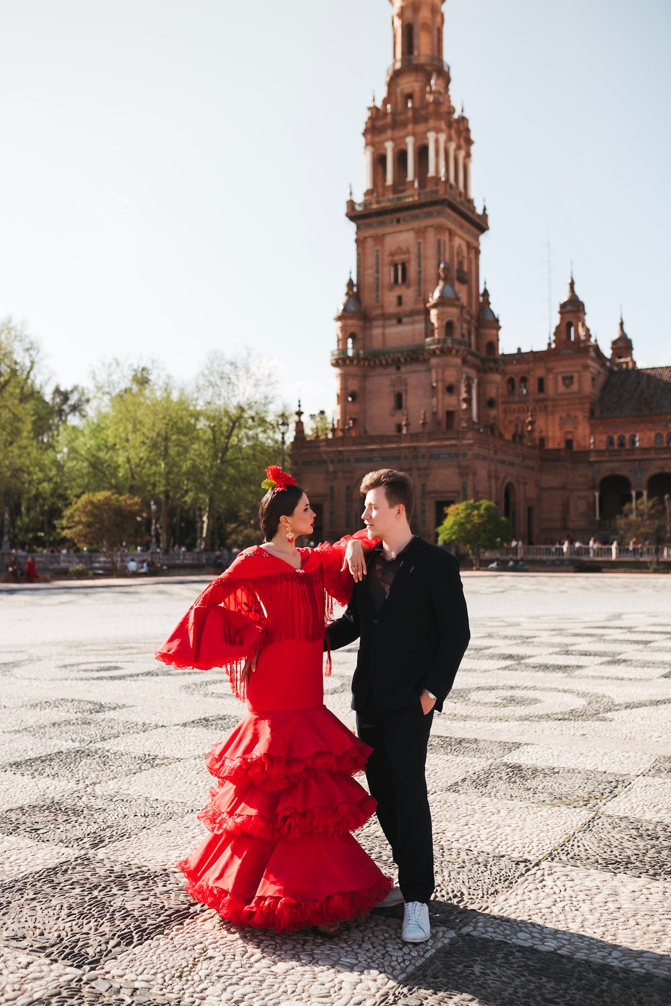 Flamenco couple dancing at Plaza de España, Seville, woman in red ruffled dress and man in black suit.