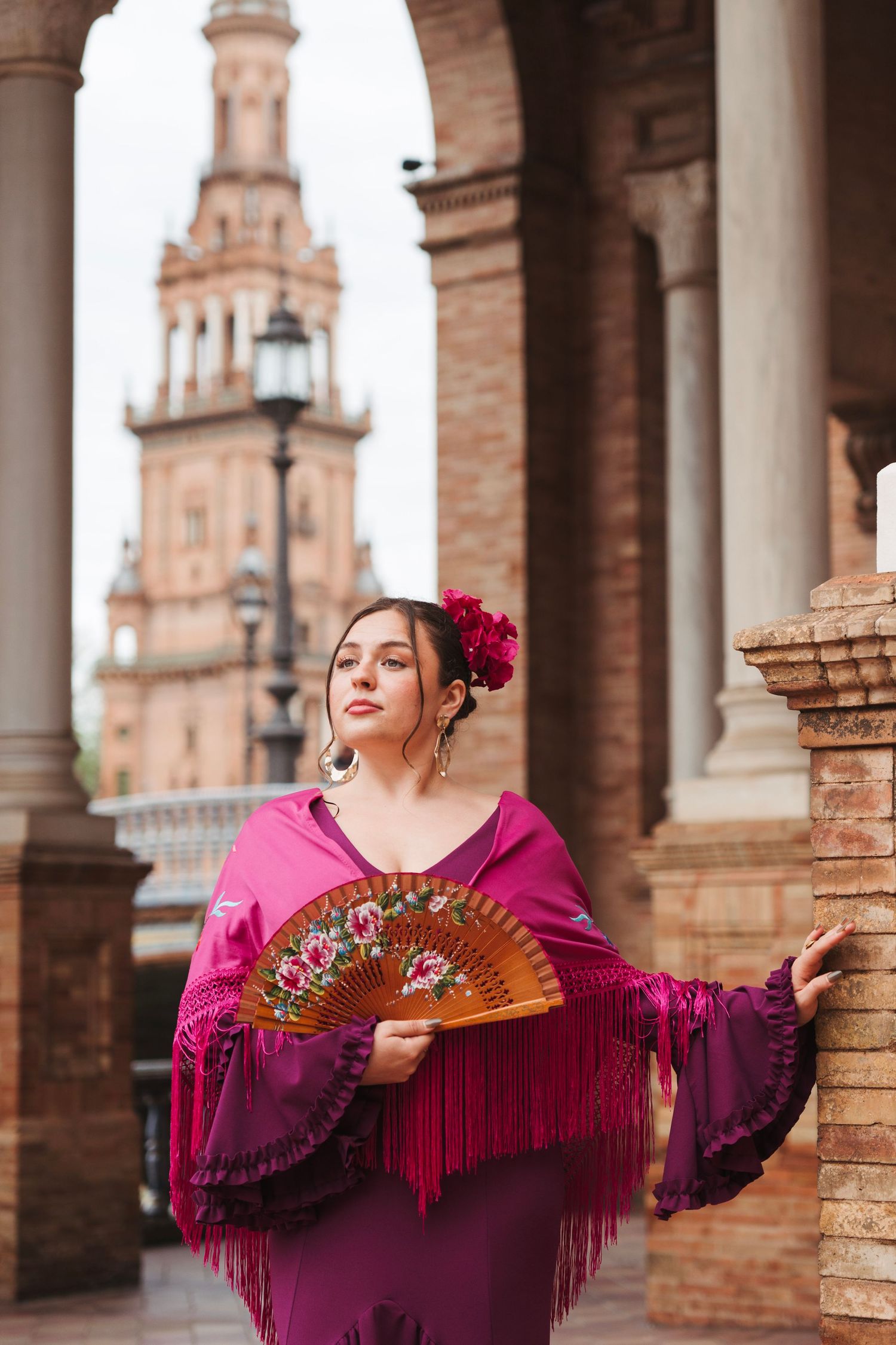 Flamenco dancer in pink dress holding decorative fan at Plaza de España, Seville.