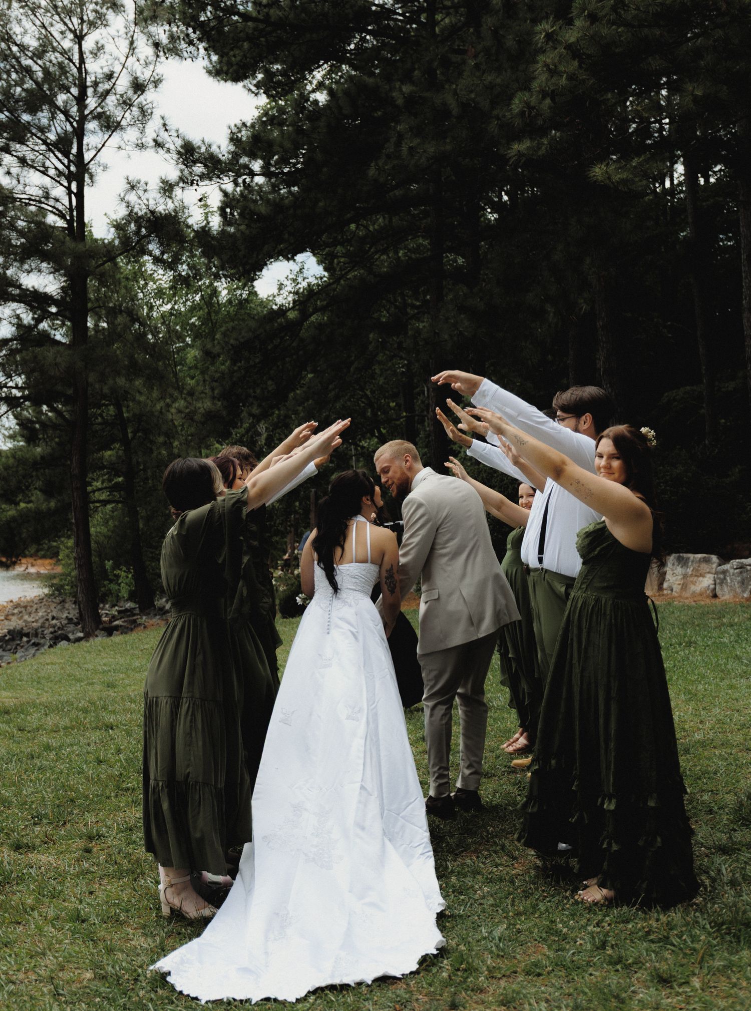 Newlyweds walking beneath raised arms during an outdoor wedding celebration
