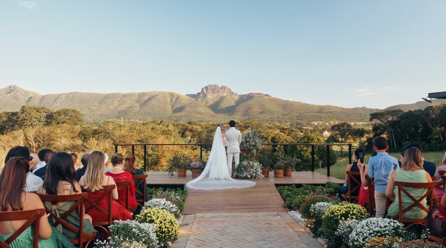 Outdoor wedding ceremony with bride and groom at the altar overlooking stunning mountain landscape.