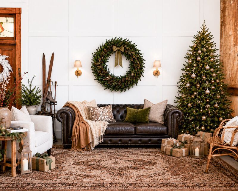 Cozy Christmas living room with wreath, decorated tree, leather sofa, gifts, and warm lighting.
