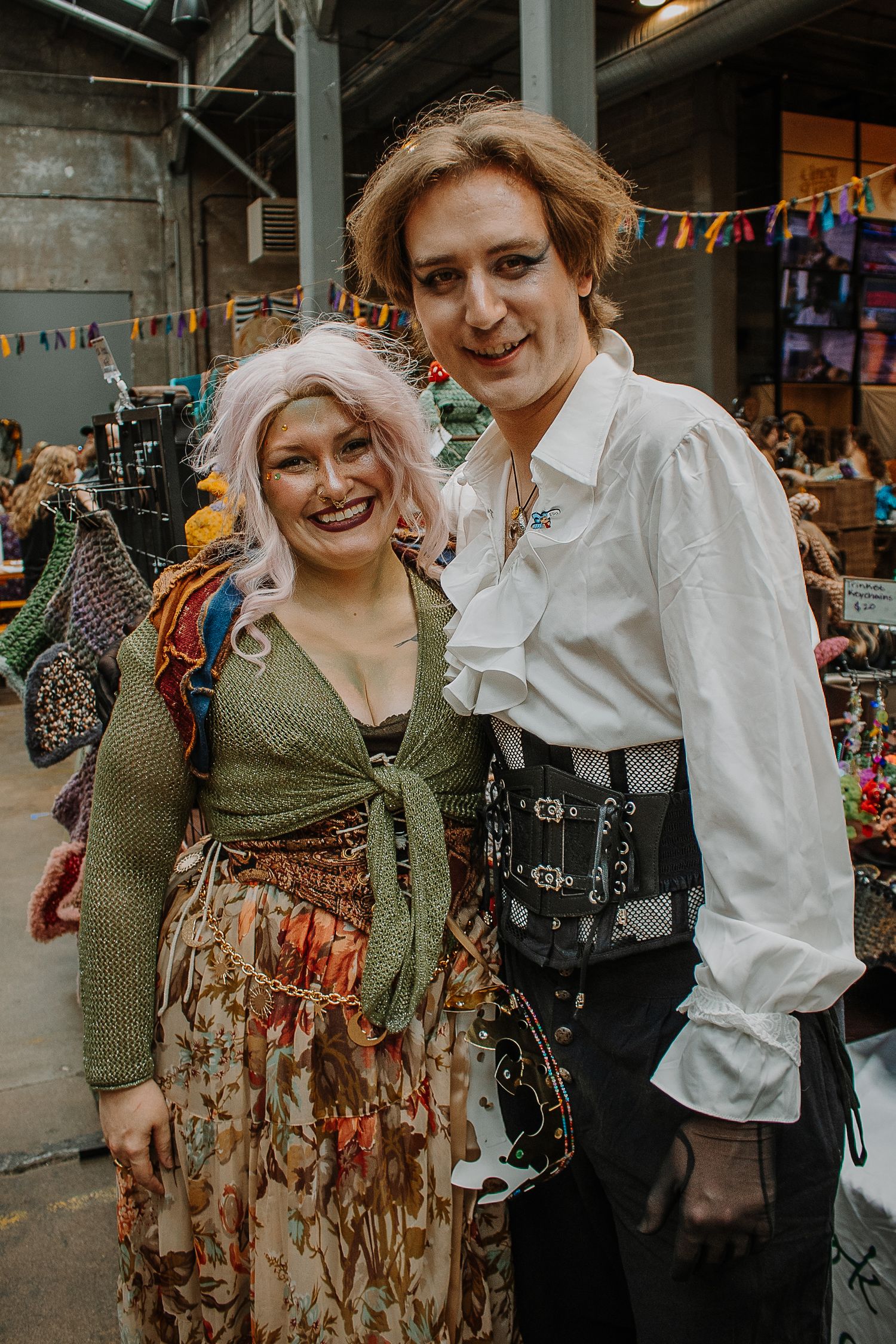 A couple in fantasy Renaissance-inspired costumes smile together at the Outer Realms Market event.