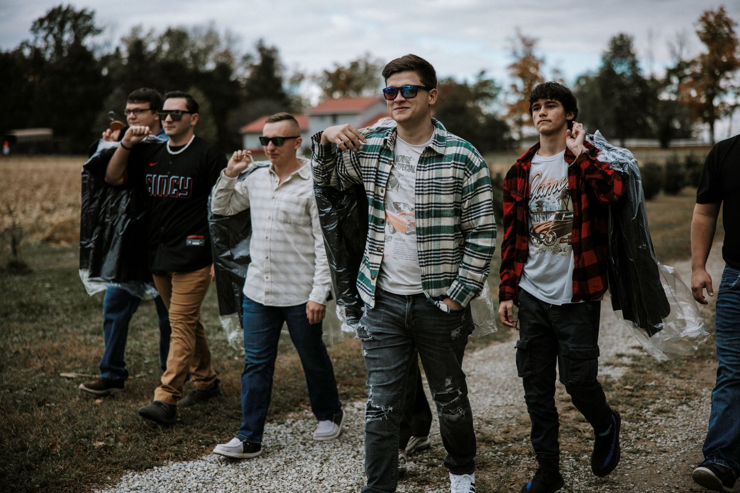 Group of young men in casual attire walking together on a gravel path at an outdoor event.