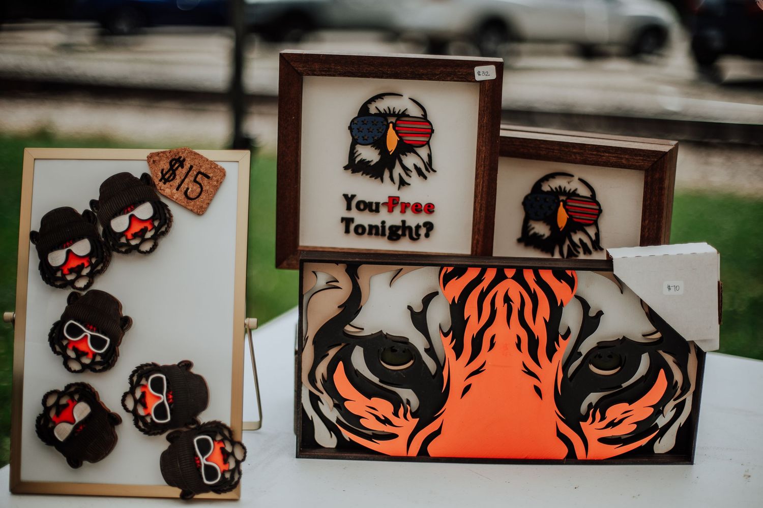 Handmade laser-cut wooden crafts including tiger and eagle designs with a You Free Tonight sign.