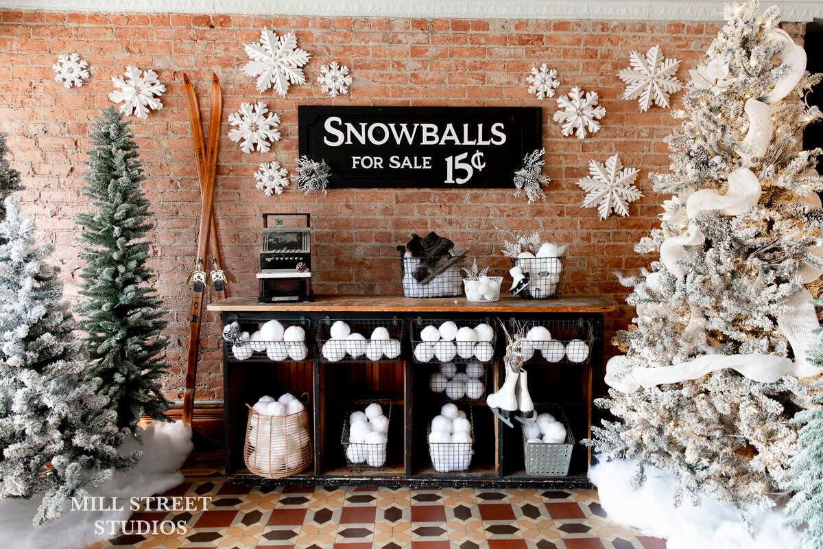 Festive holiday display with flocked Christmas trees, large snowflake decorations, and a vintage Snowballs For Sale 15 cents sign.