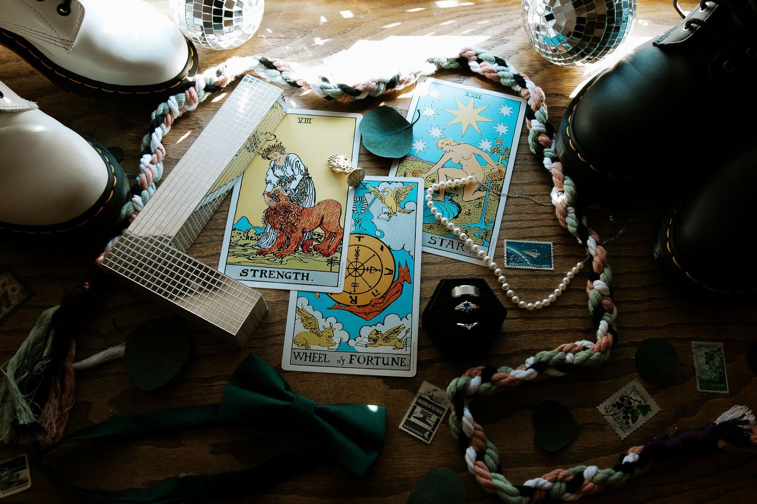 Tarot cards including Strength and Wheel of Fortune spread on wooden table with bow tie and accessories.