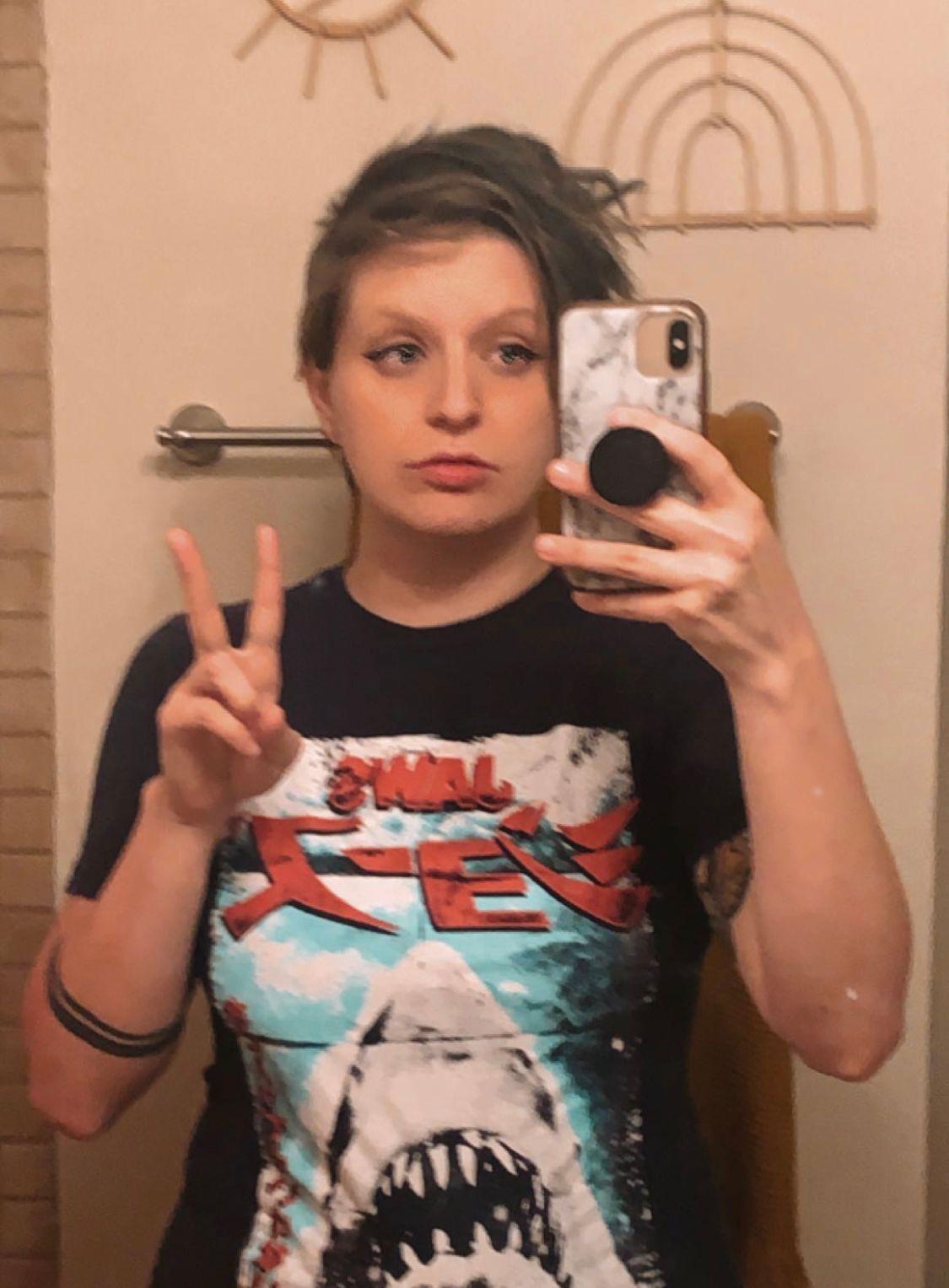 Person taking mirror selfie wearing Jaws movie t-shirt flashing peace sign.