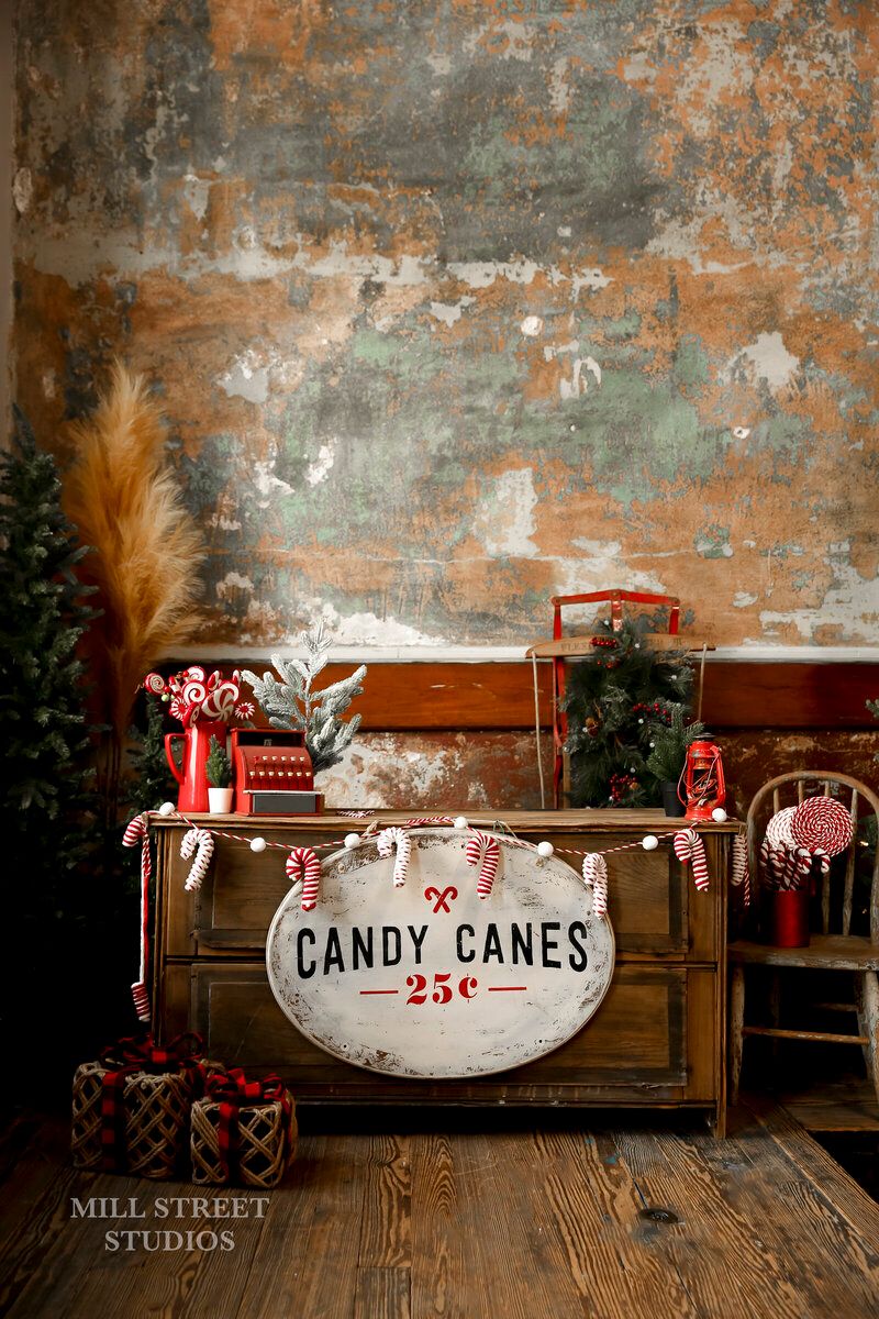 Rustic Christmas candy cane sign display on vintage wooden dresser with holiday decorations and distressed wall backdrop.