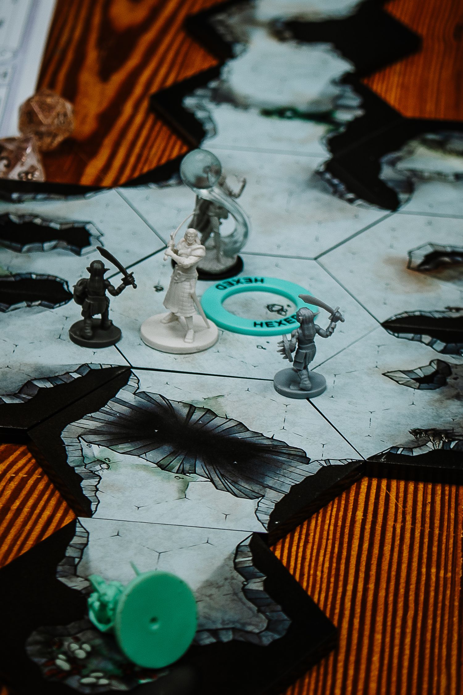 Tabletop RPG miniature figures arranged on a hex grid battle map on a wooden table.