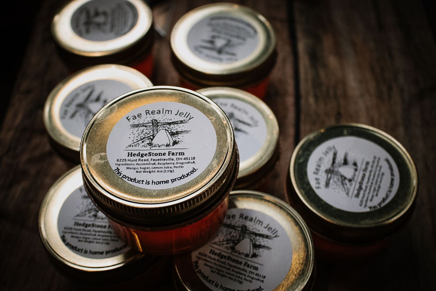 Small glass jars of Fae Realm Jelly from HedgeStone Farm on rustic wood.