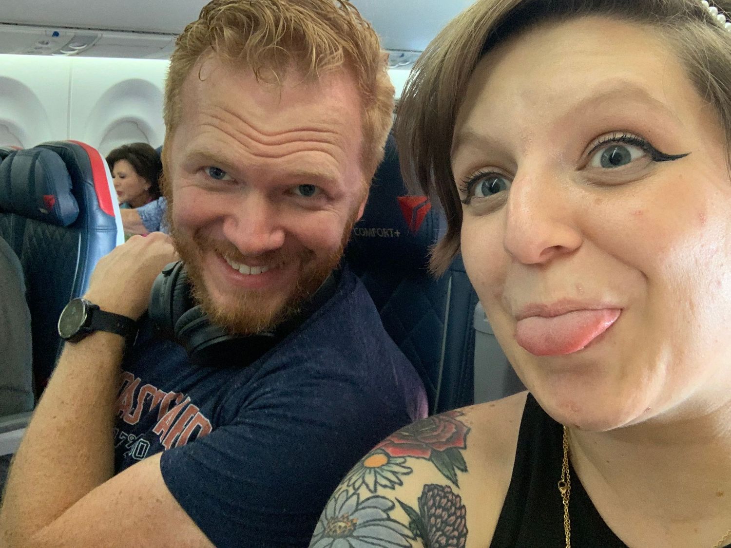 Couple making silly faces while taking selfie on airplane together.