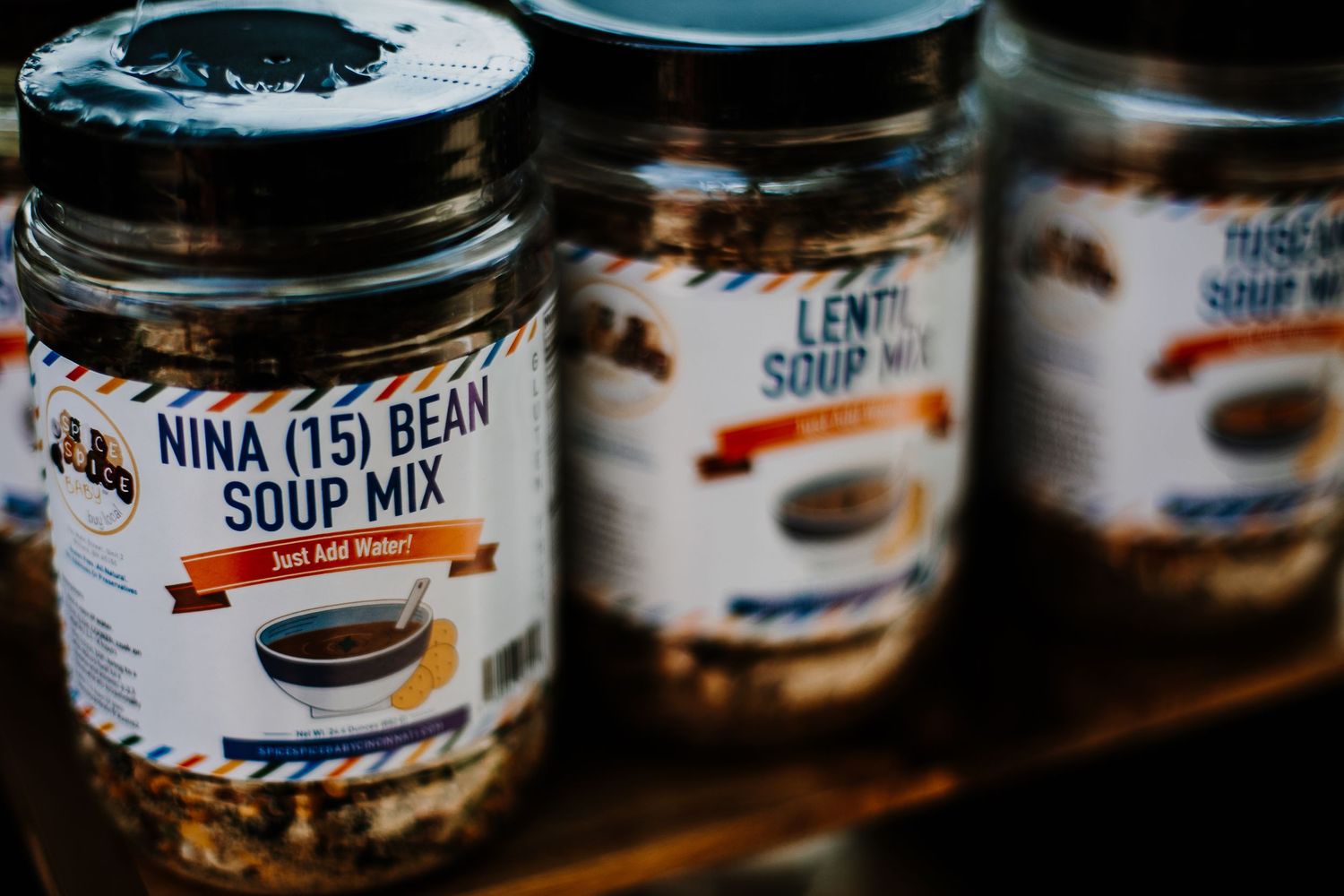 Jars of Nina 15 Bean Soup Mix and Lentil Soup Mix displayed on a wooden shelf.