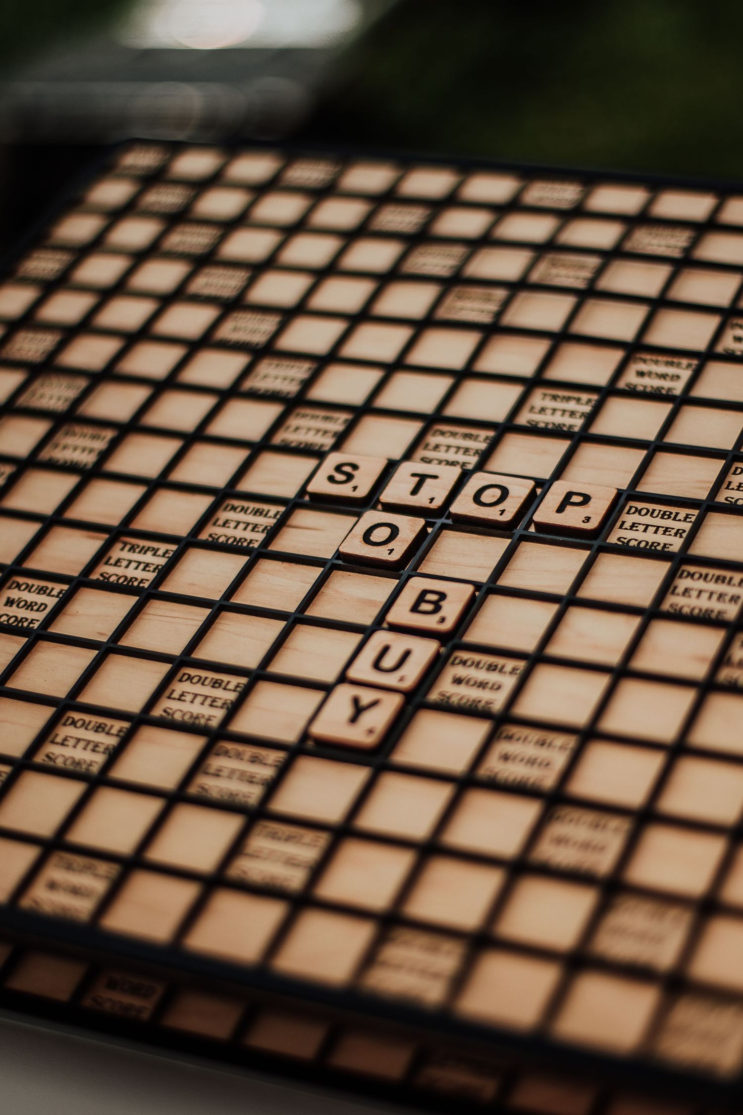 Scrabble board with tiles spelling STOP and BUY as a creative retail marketing display.