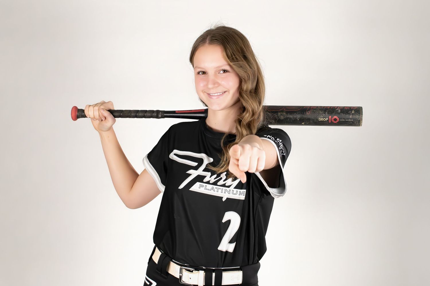 Young softball player in black Fury jersey number 2 holding bat over shoulder.