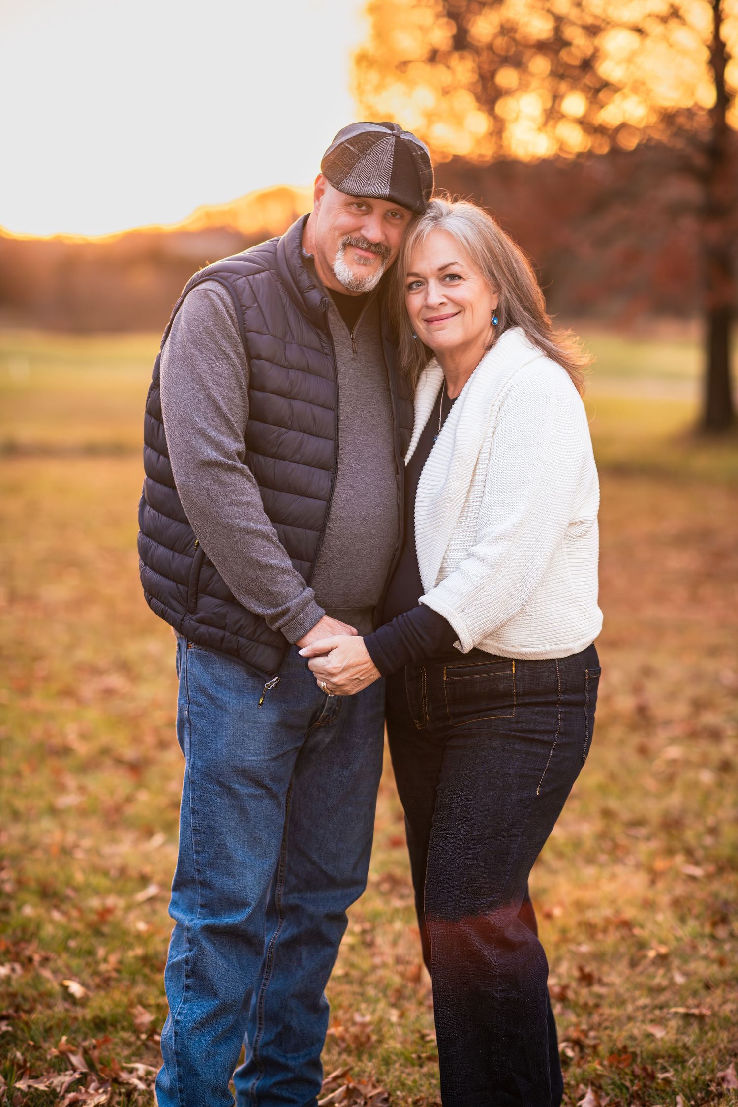 Couple holding hands and smiling together during a warm autumn sunset outdoor portrait.