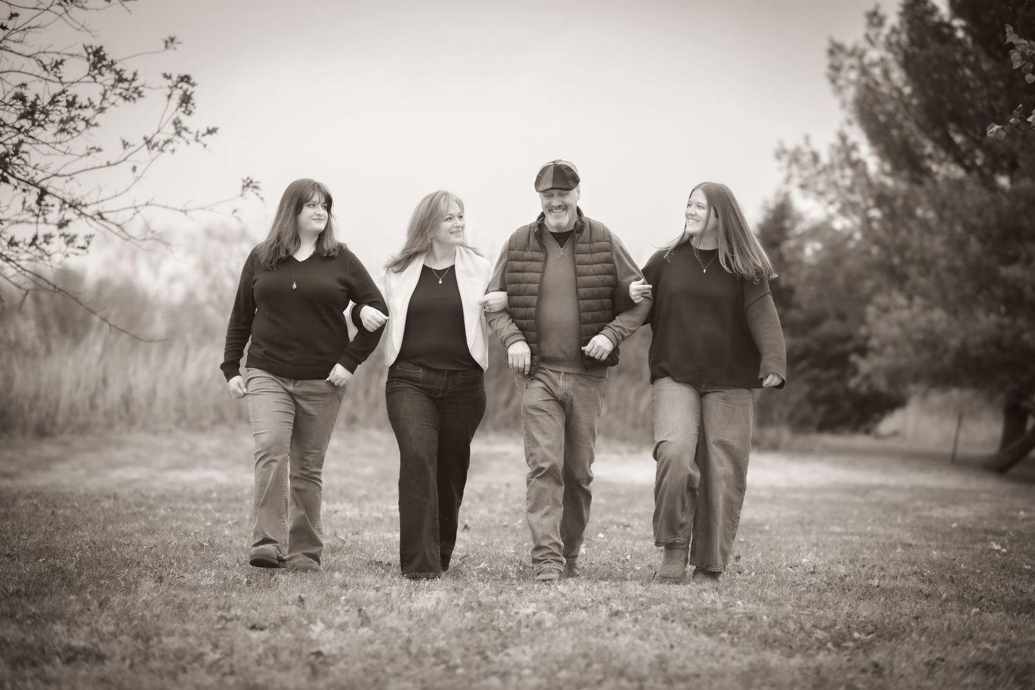 Black and white photo of a family of four walking together through an open field.