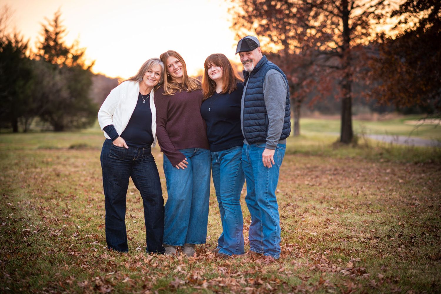 Family of four posing together at sunset in a fall outdoor setting.