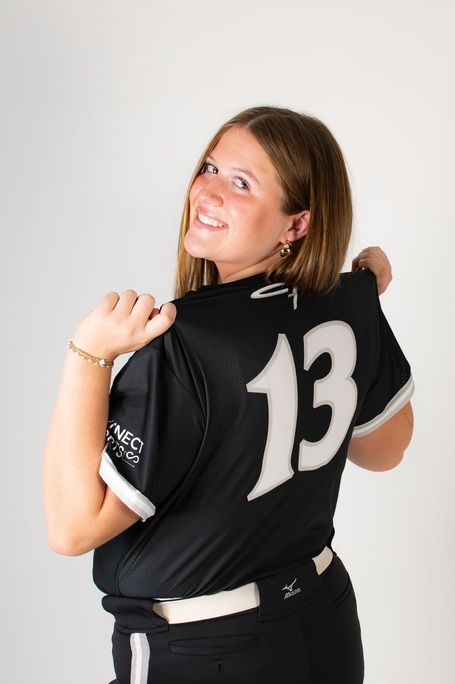 Softball player showing back of black number 13 jersey over shoulder.