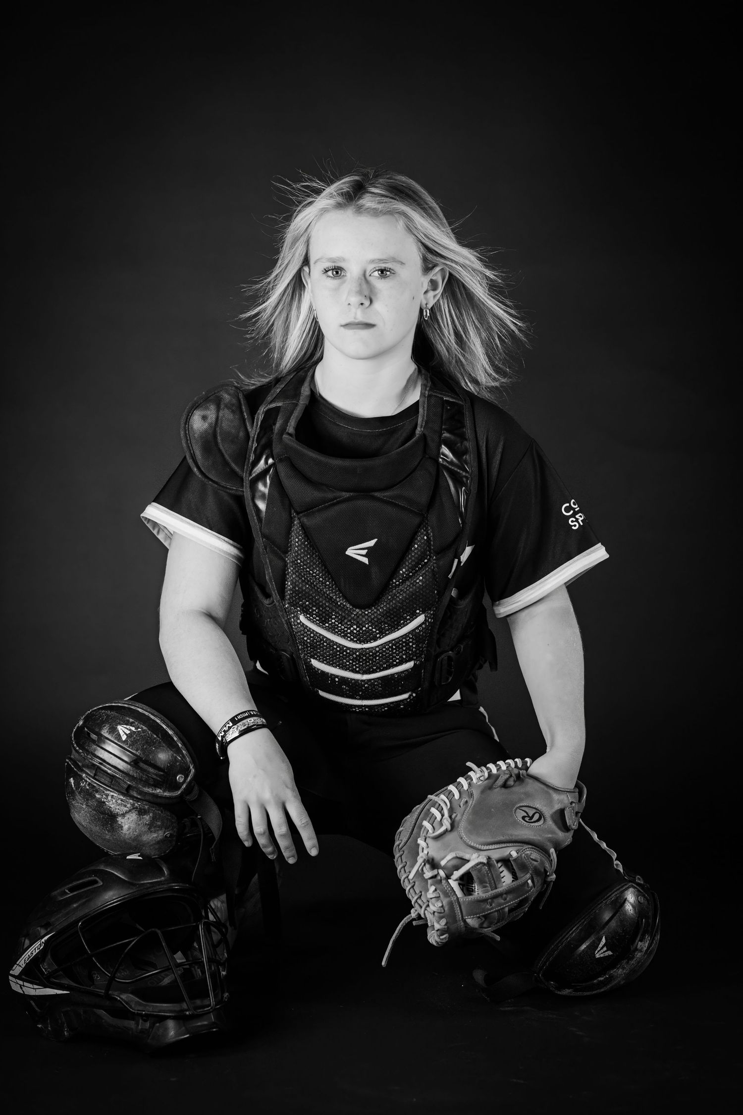 Black and white photo of female softball catcher in Easton gear with equipment.