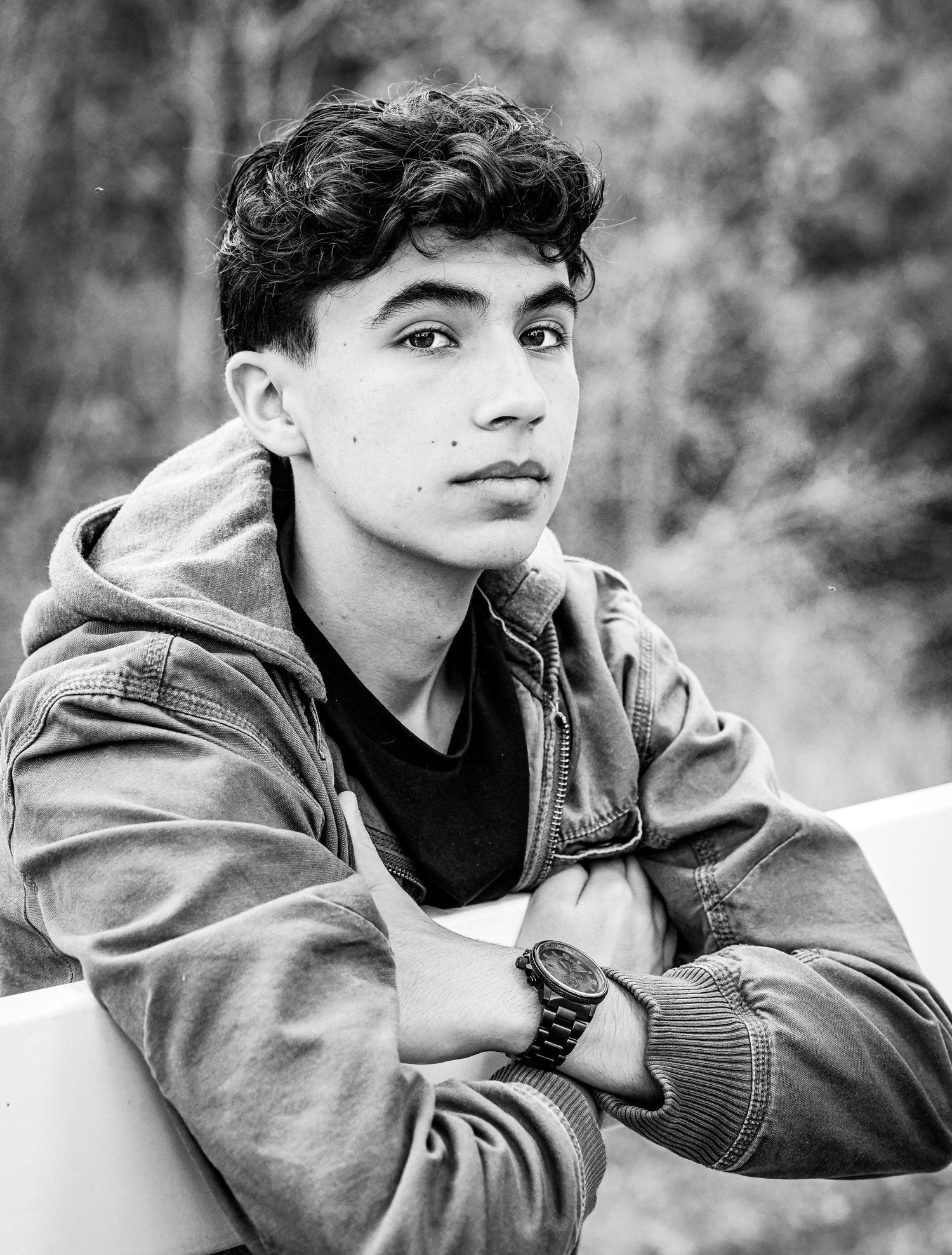 Black and white portrait of teen boy in hoodie with arms crossed.