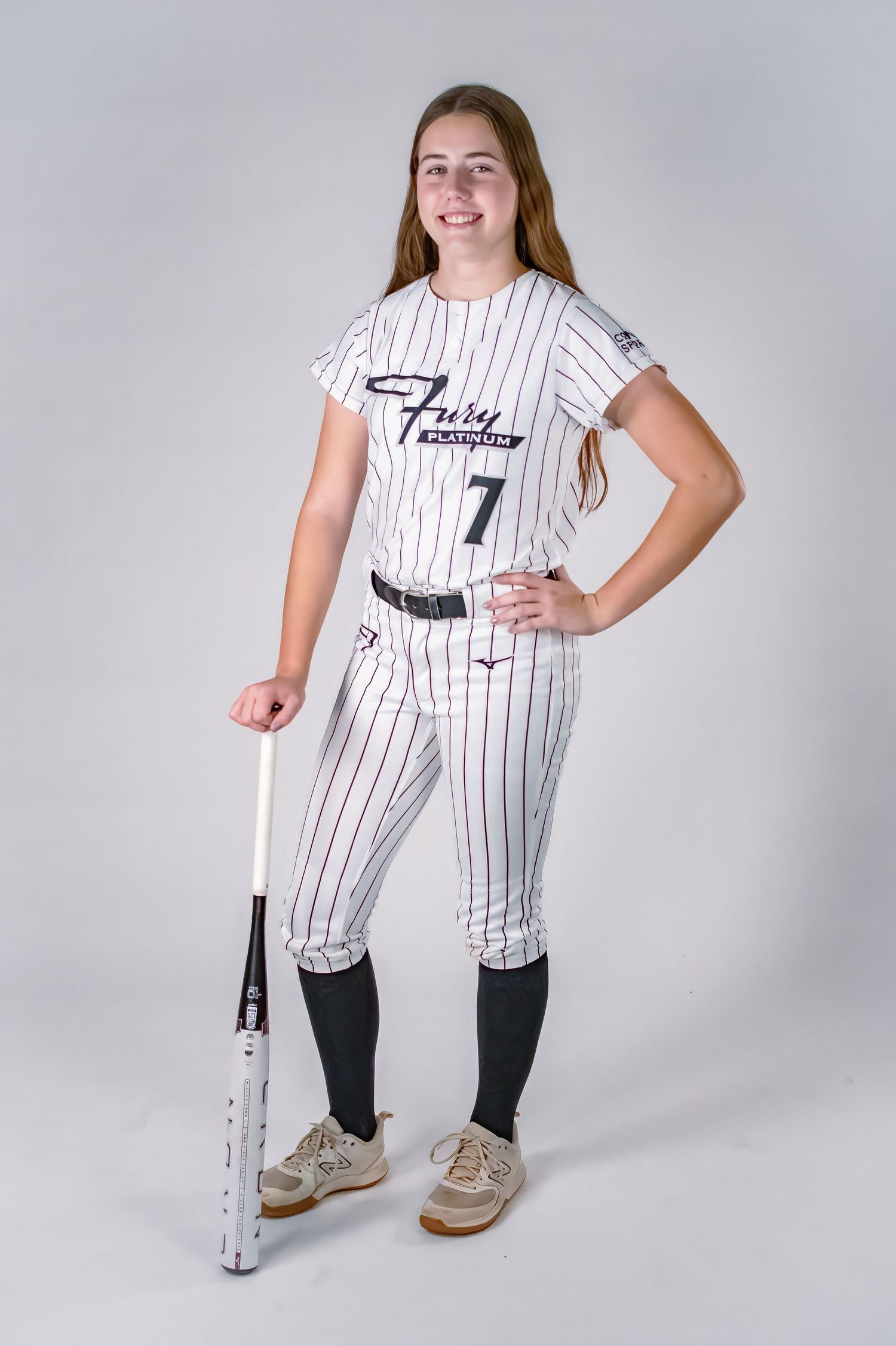 Softball player in white pinstripe Fury Platinum jersey number 7 posing with a bat in a studio.