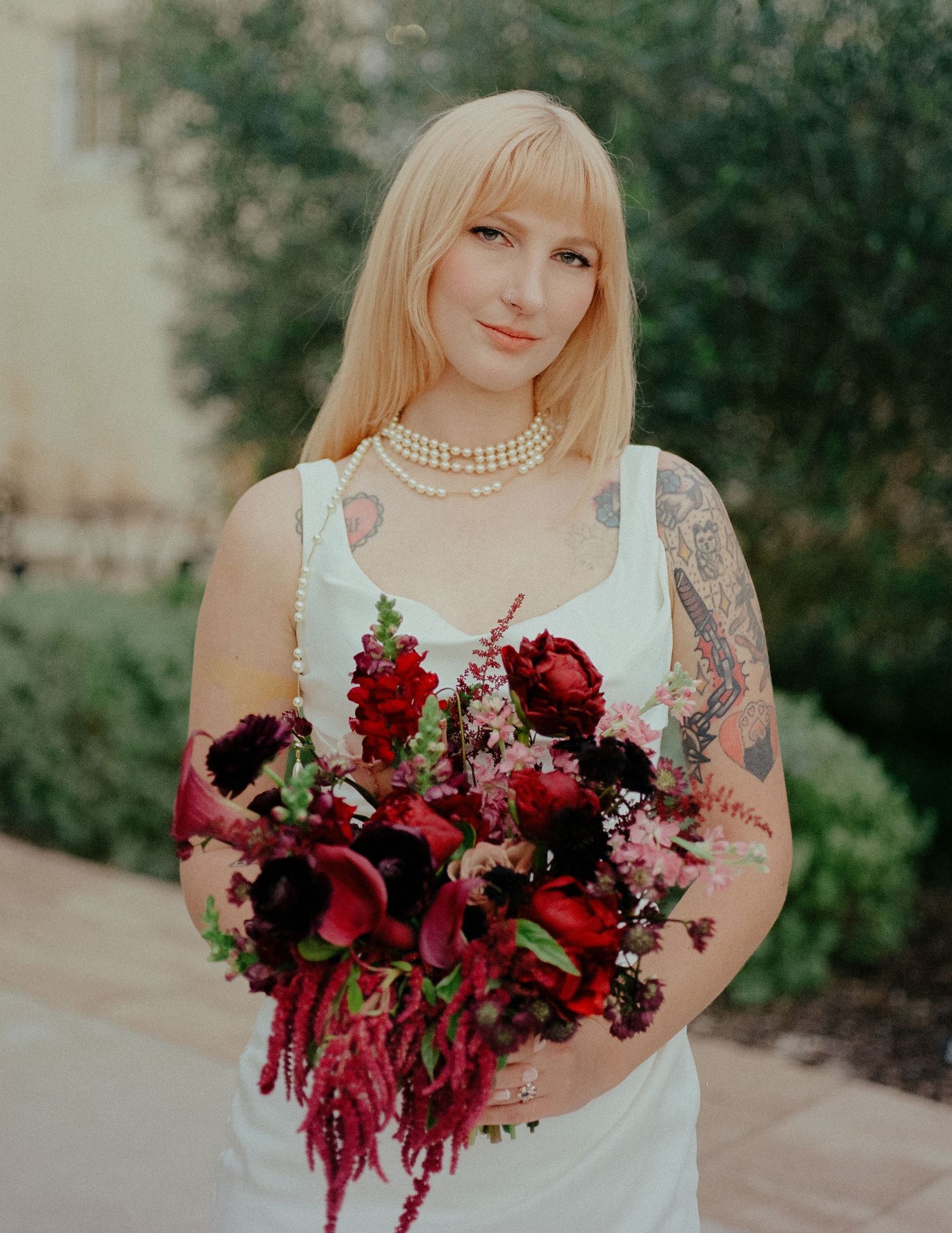 A wedding bouquet features deep red and burgundy flowers with cascading elements against a light background.
