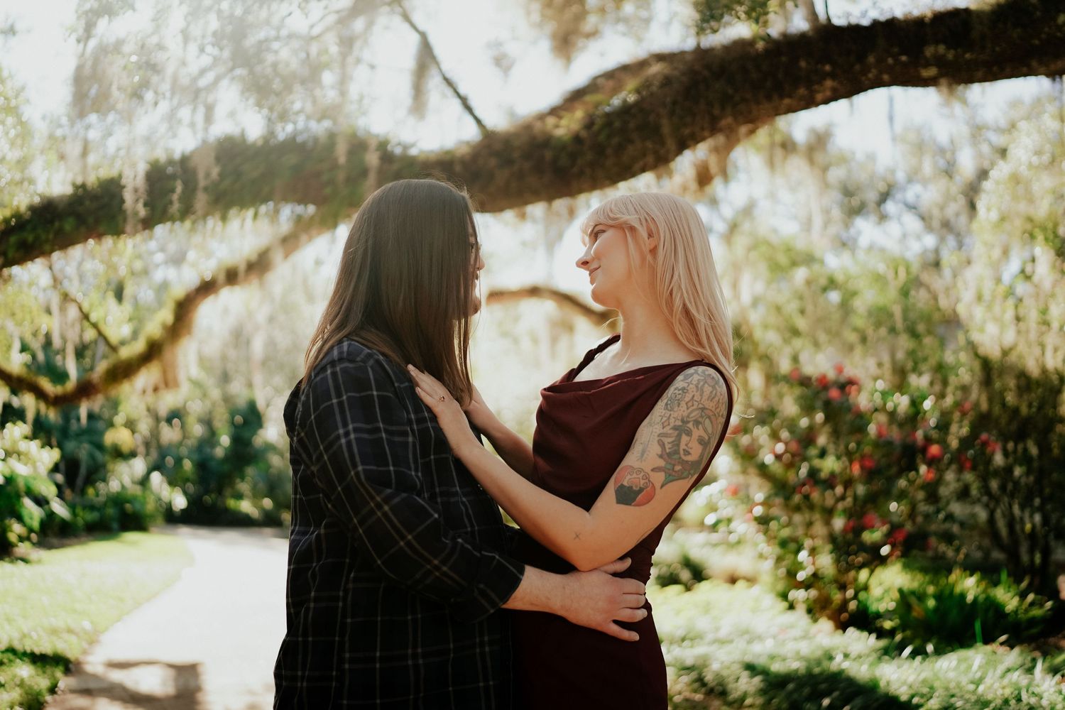A tender moment between two people embracing in a garden under flowering trees.